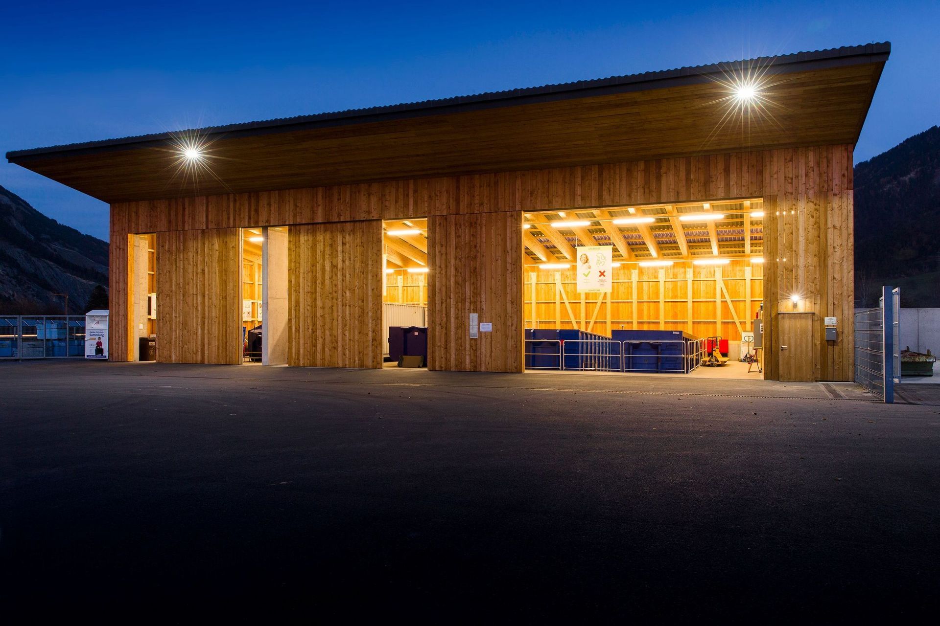 Ein großes Holzgebäude mit einem großen Garagentor ist nachts beleuchtet.