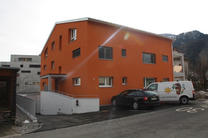 Ein orangefarbenes Gebäude mit einem davor geparkten weißen Lieferwagen