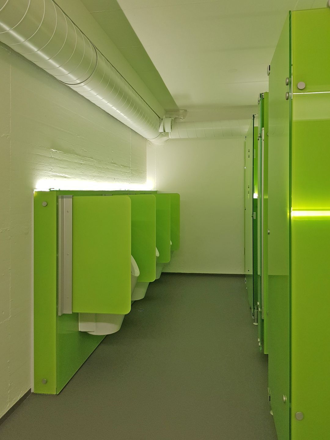 Eine Reihe grüner Urinale in einer öffentlichen Toilette.