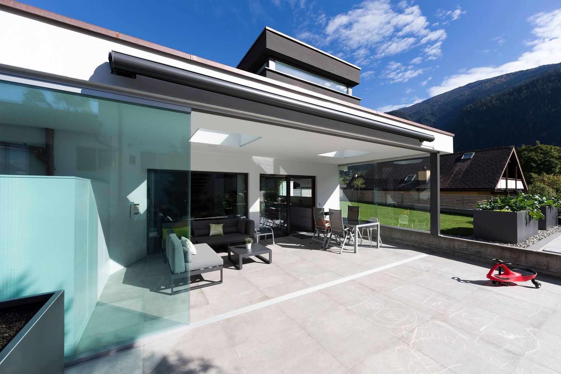 Ein modernes Haus mit Terrasse und Bergen im Hintergrund
