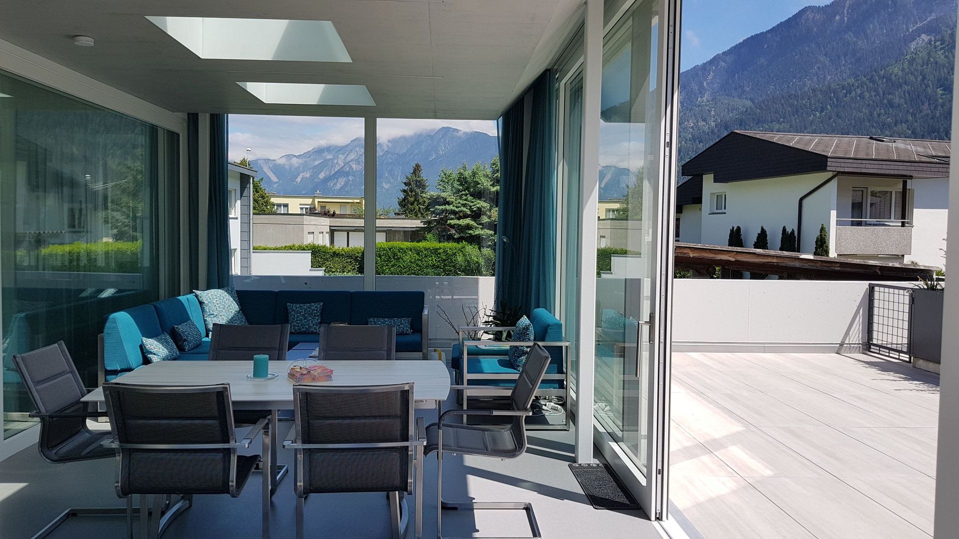 Eine Terrasse mit Tisch und Stühlen und Bergen im Hintergrund.