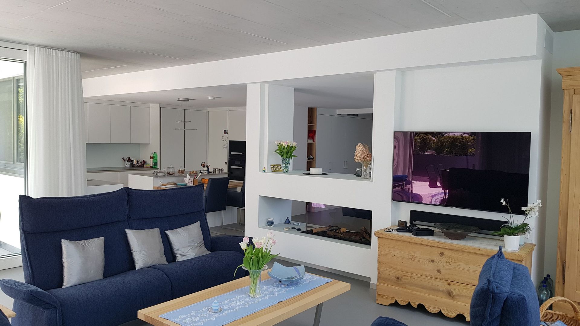 Ein Wohnzimmer mit blauem Sofa, Couchtisch und Fernseher.