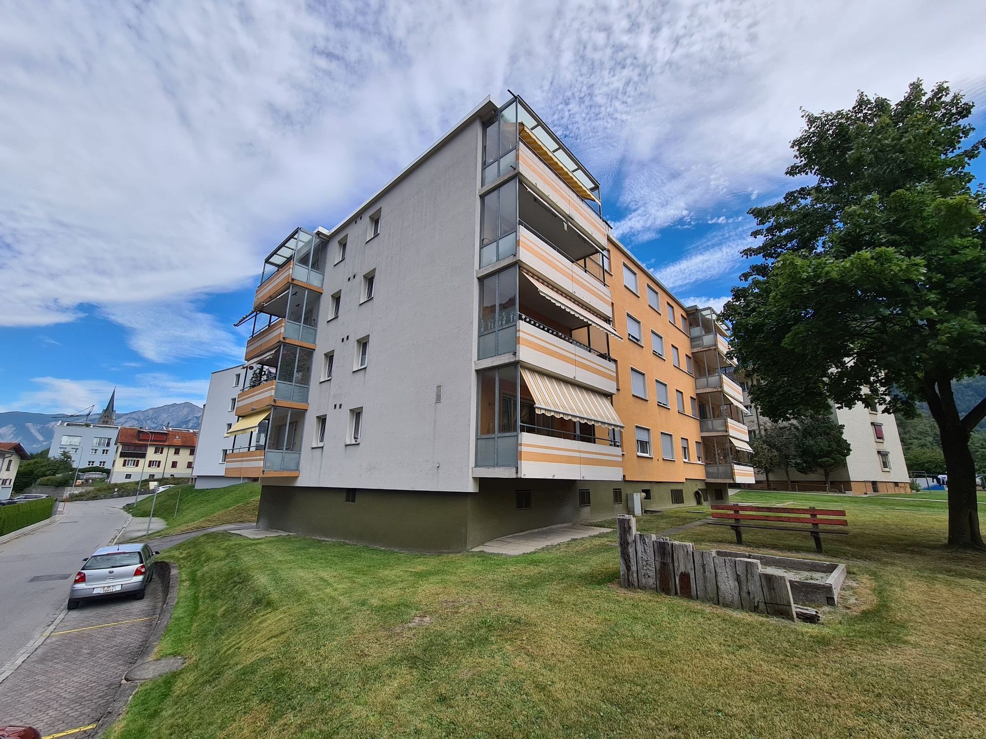 Auf einem grasbewachsenen Hügel steht ein großes Wohnhaus.