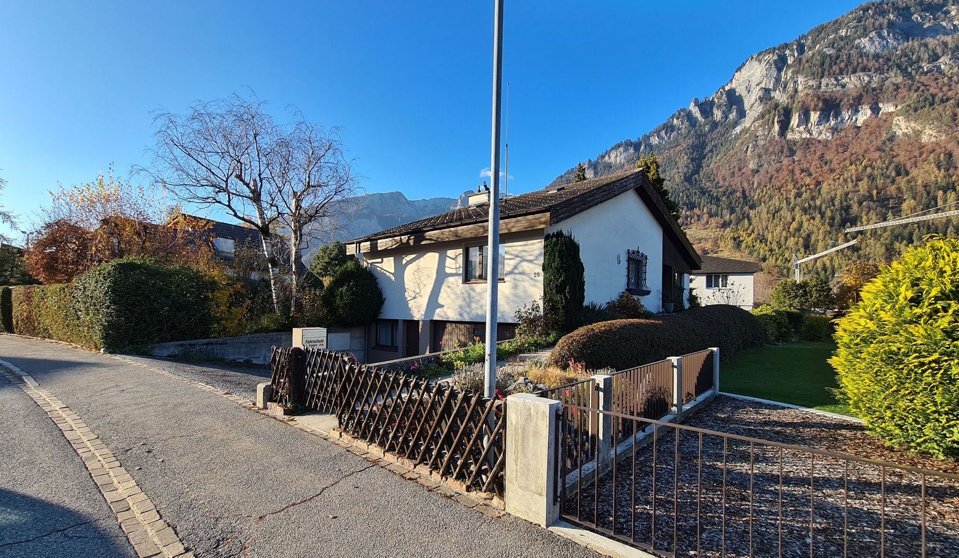 Ein Haus mit Zaun und Bergen im Hintergrund