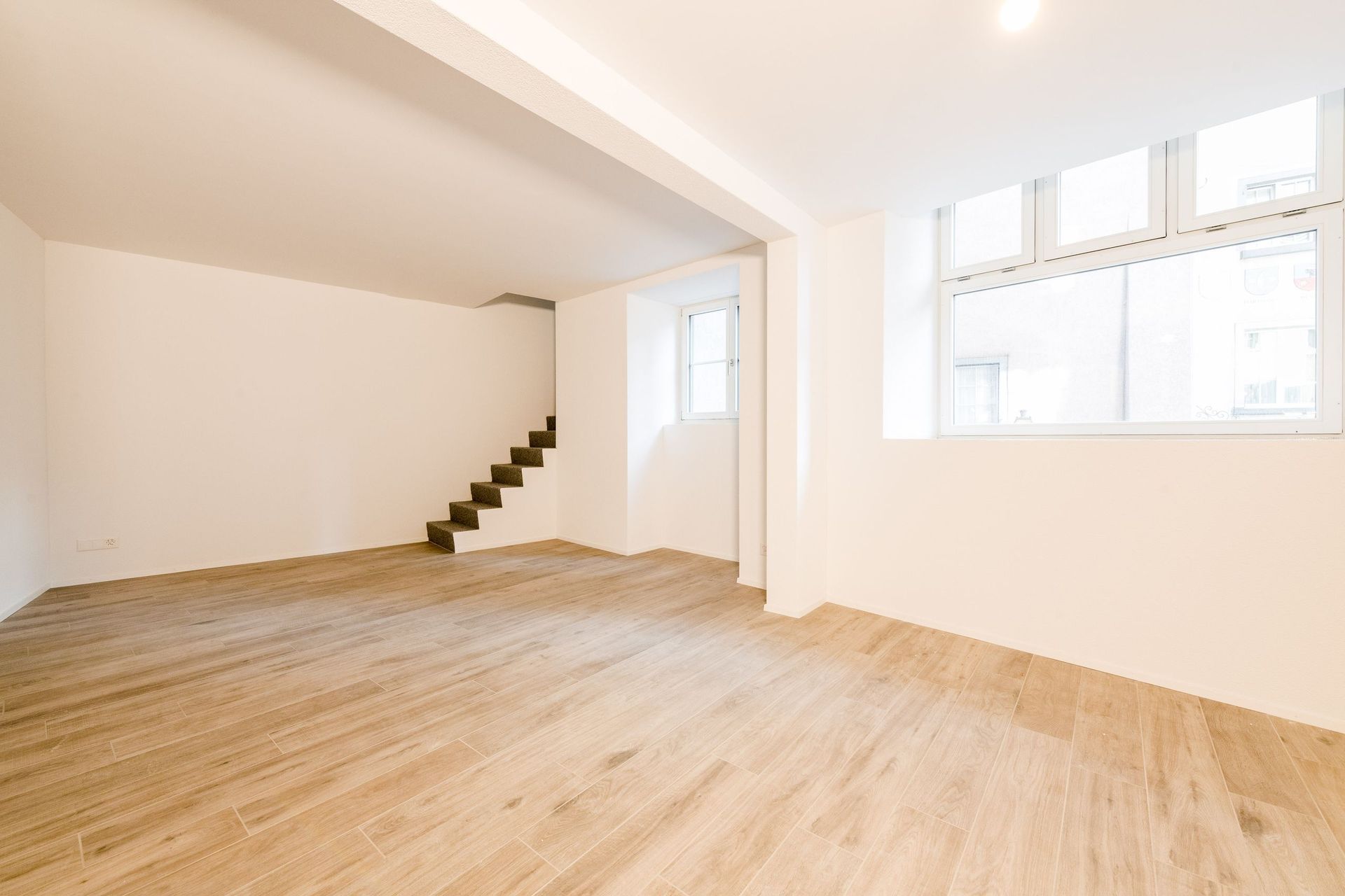 Ein leeres Wohnzimmer mit Holzboden und einer Treppe, die in den zweiten Stock führt.