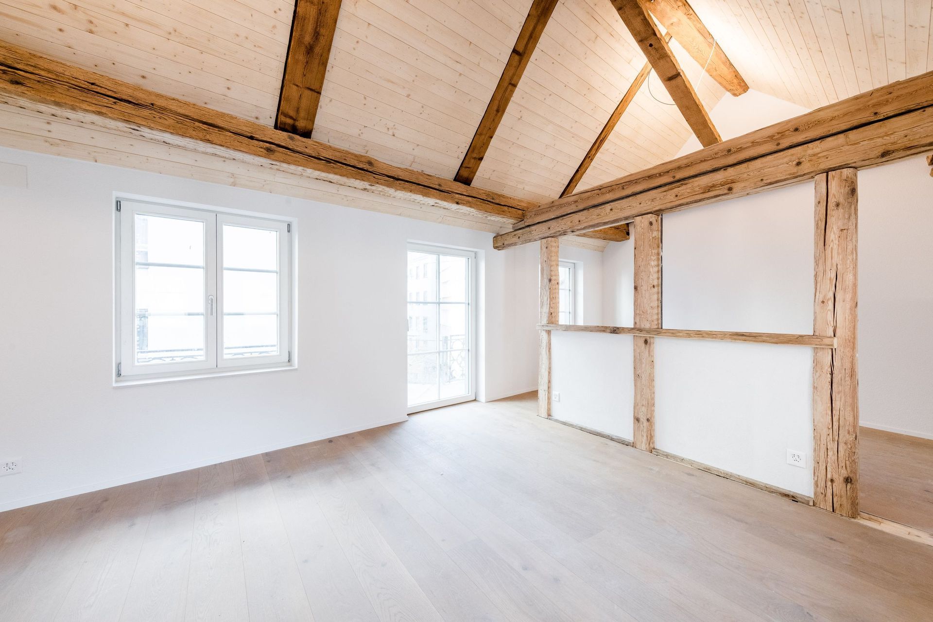 Ein leerer Raum mit Holzbalken und weißen Wänden.