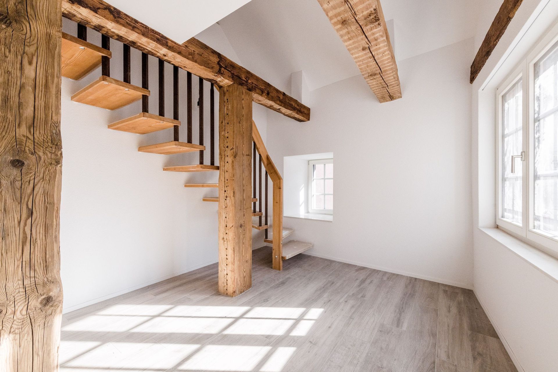 Ein leerer Raum mit einer Wendeltreppe und Holzbalken.
