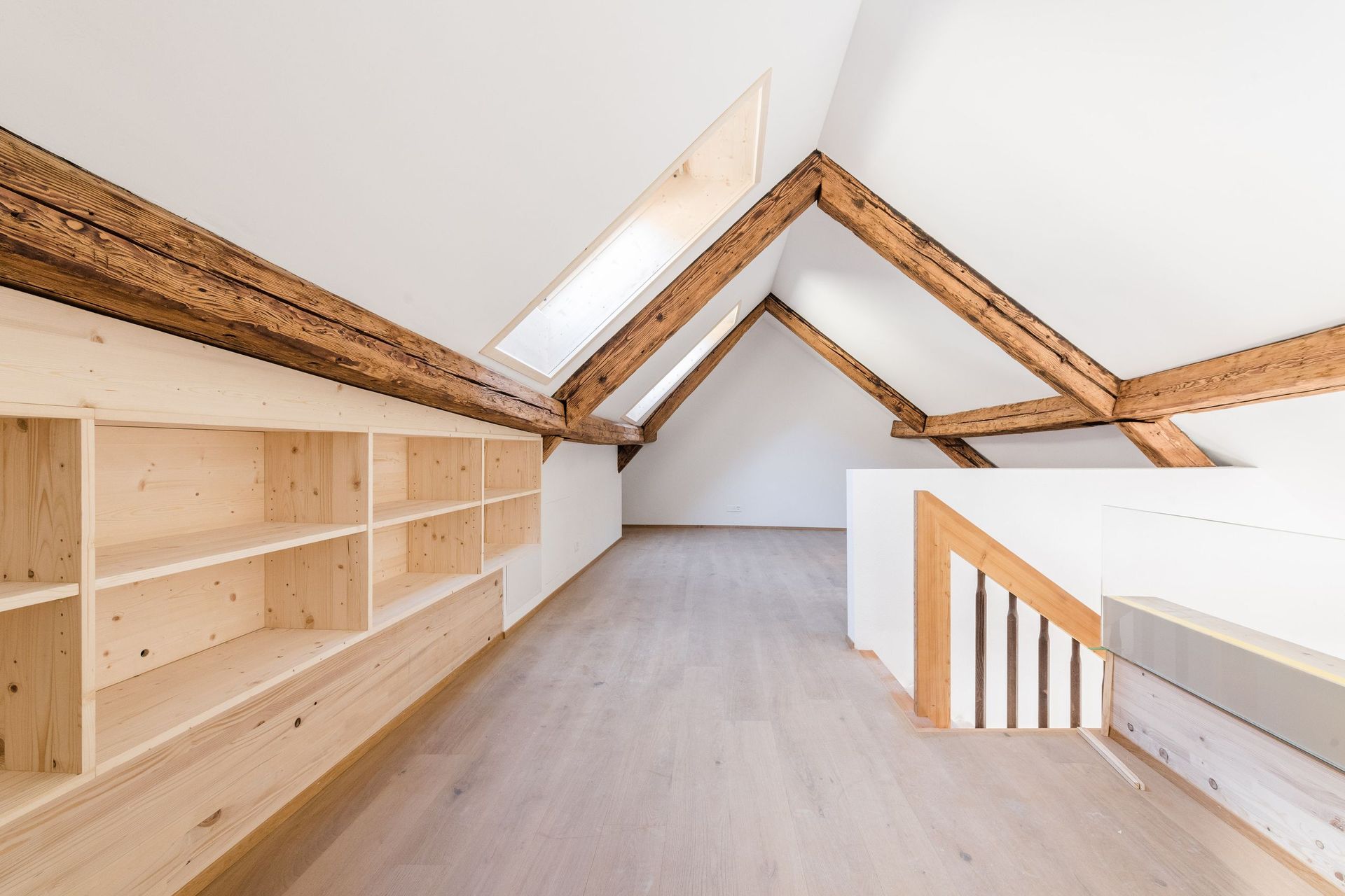 Ein leerer Dachboden mit Holzregalen und einem Holzgeländer.