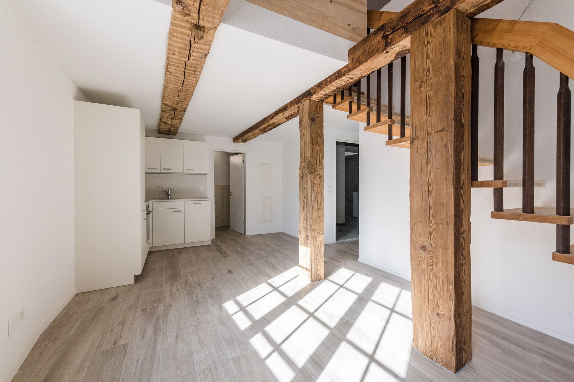 Ein leerer Raum mit einer Wendeltreppe und Holzbalken.