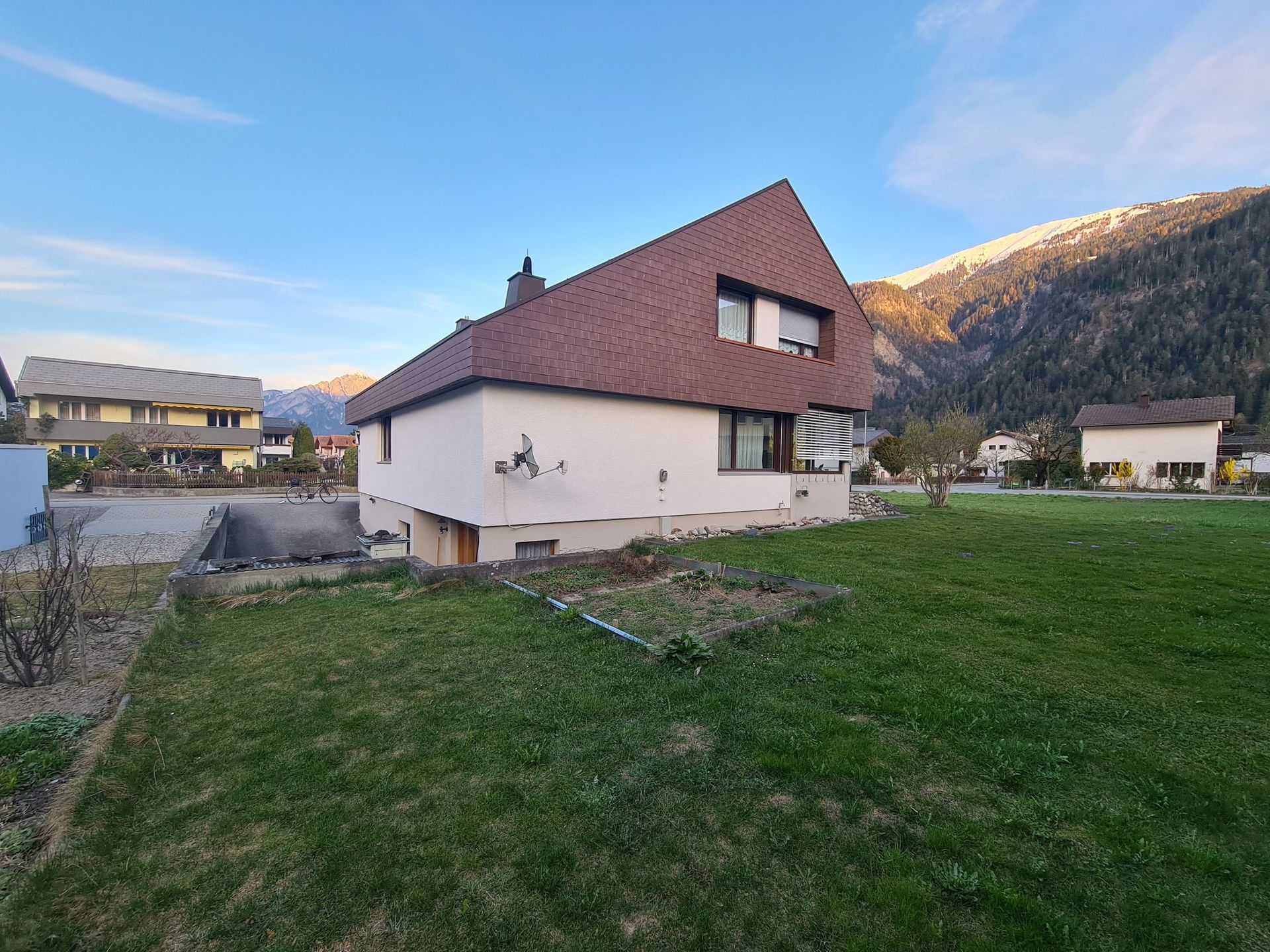 Ein weißes Haus mit rotem Dach und einer großen Wiese davor.