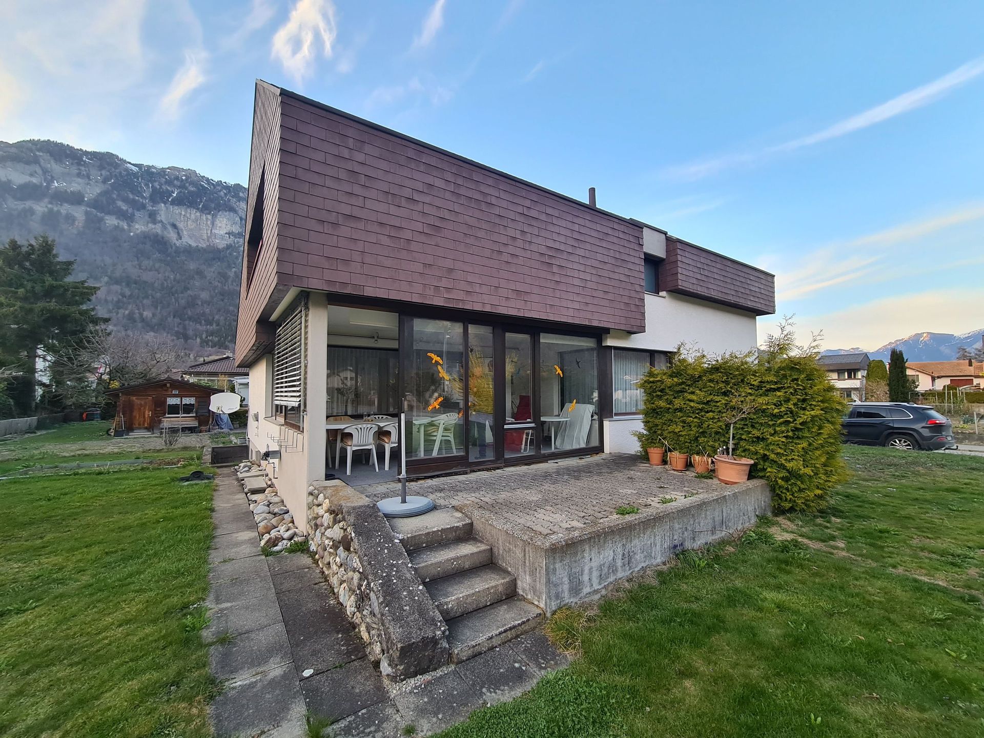 Ein kleines weißes Haus mit braunem Dach steht inmitten einer üppigen grünen Wiese.