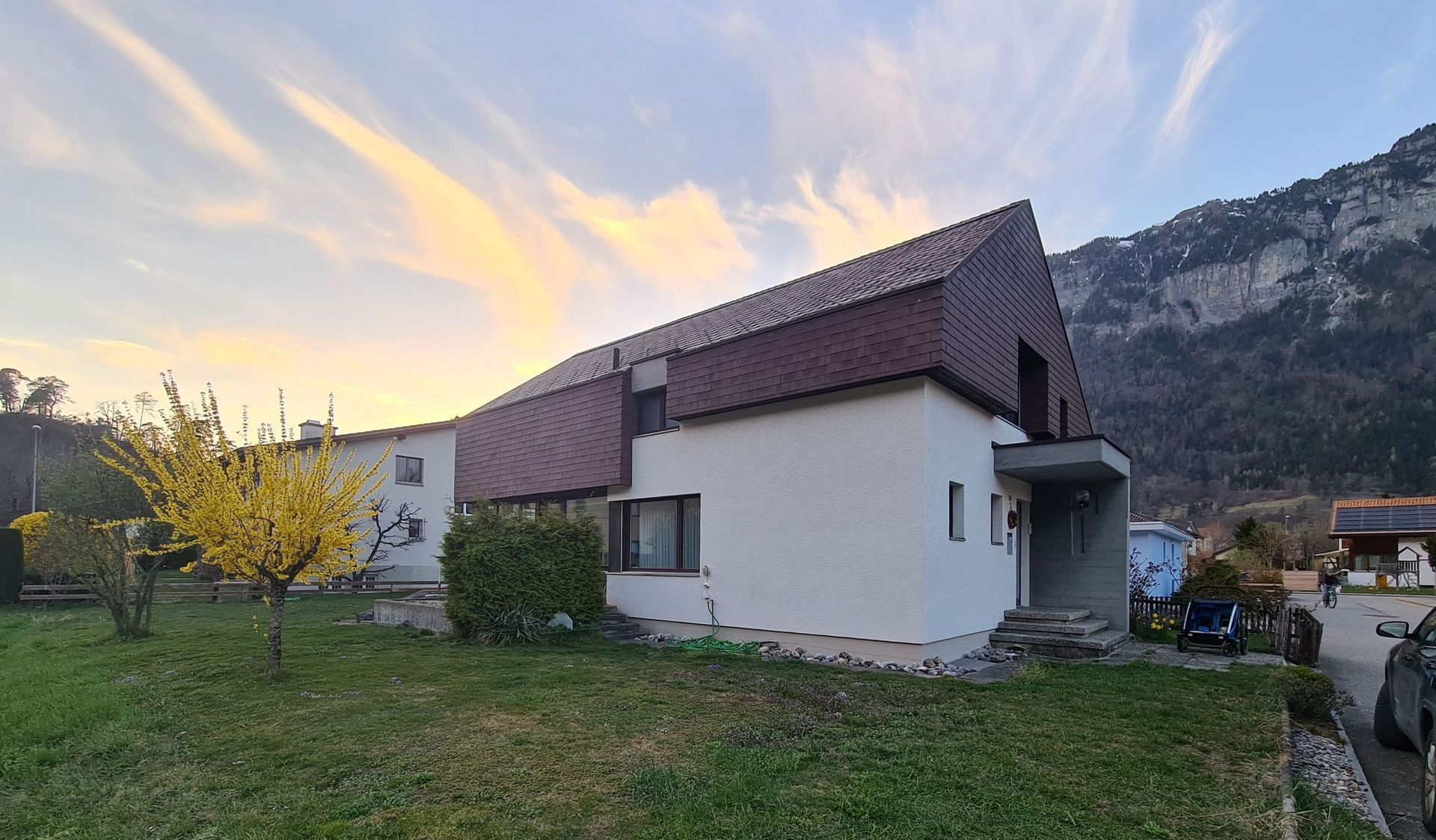 Ein weißes Haus mit braunem Dach steht inmitten einer üppigen grünen Wiese.