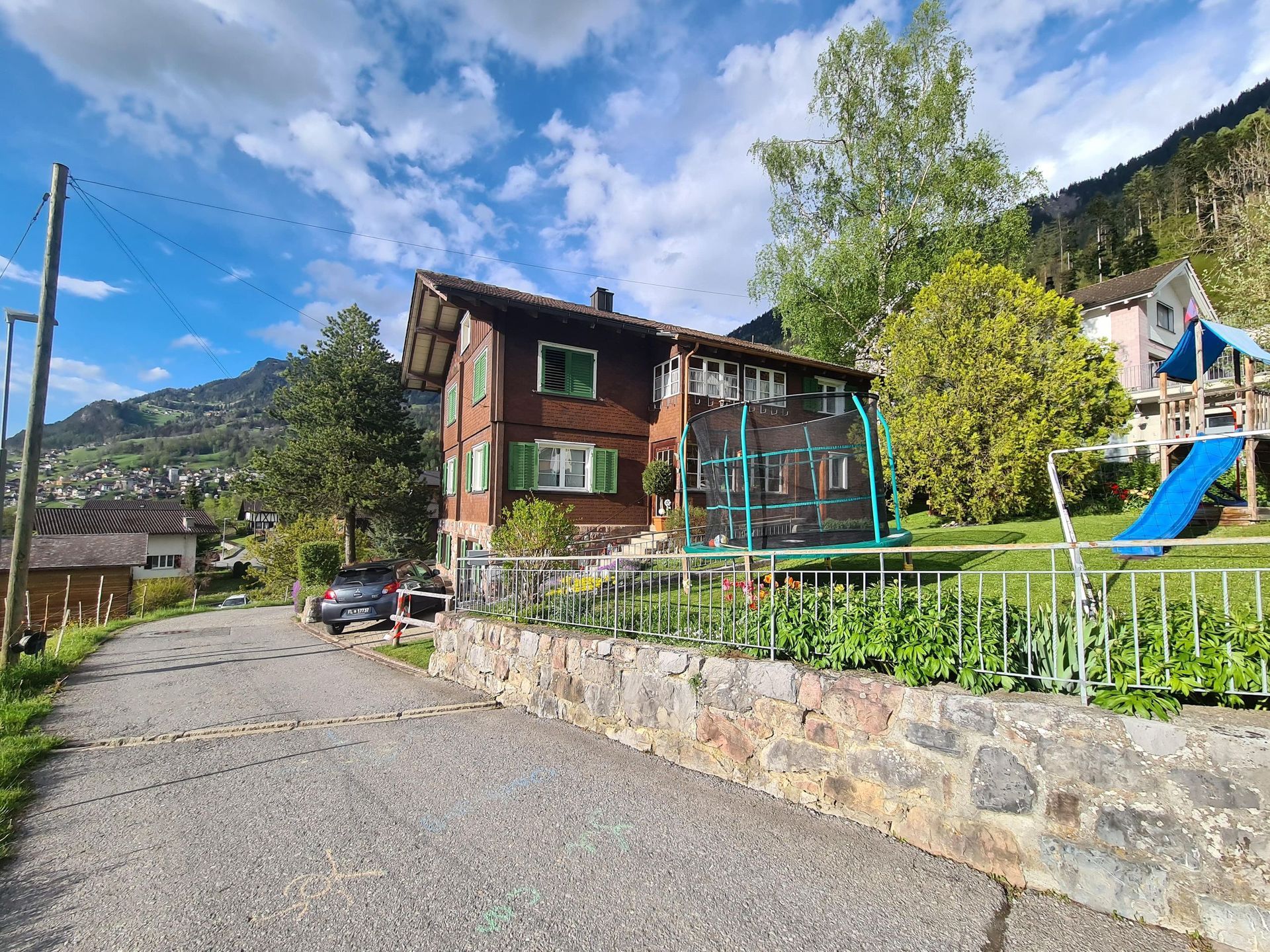 Ein Haus mit einem Trampolin davor und einem Spielplatz im Hinterhof.