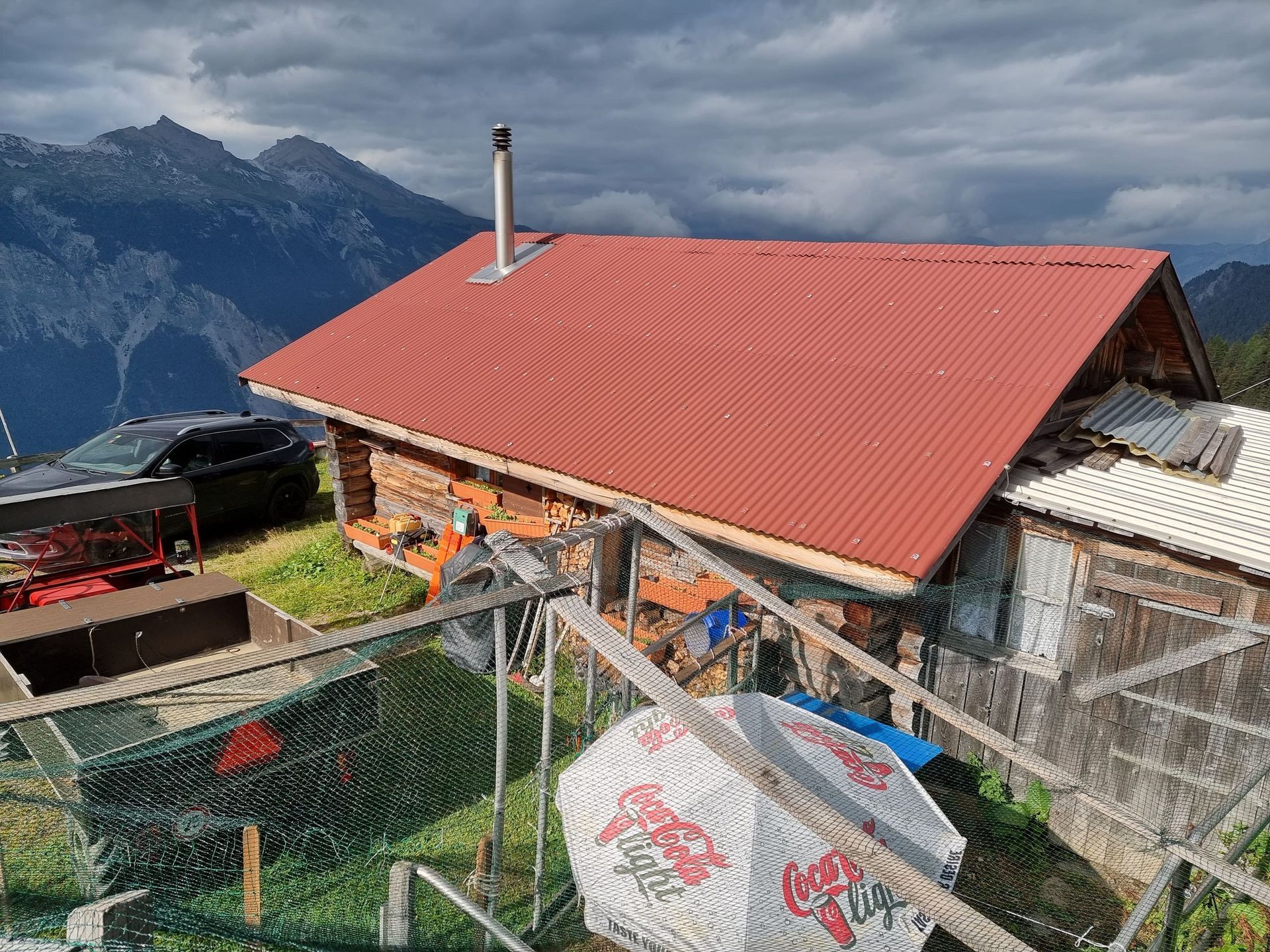 Ein Haus mit rotem Dach steht auf einem Hügel mit Bergen im Hintergrund.