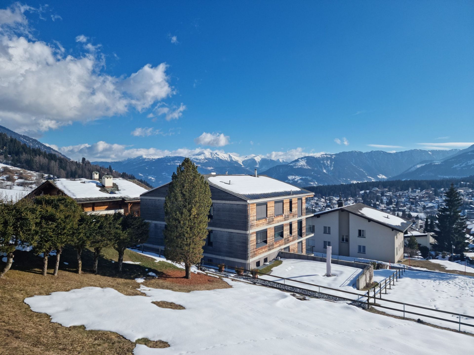 Eine verschneite Landschaft mit einem Gebäude im Vordergrund und Bergen im Hintergrund