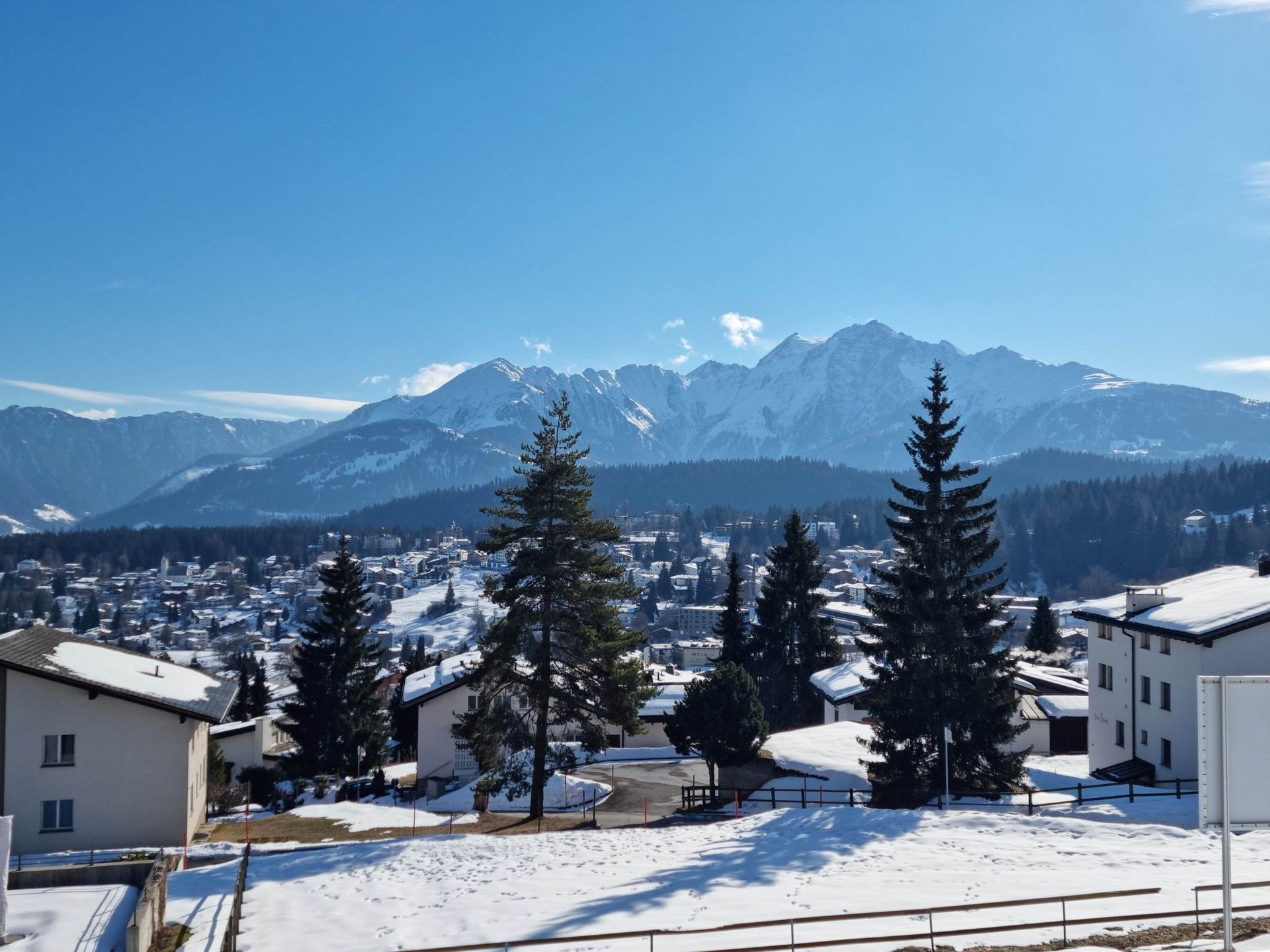 Eine verschneite Landschaft mit Bergen im Hintergrund und Häusern im Vordergrund
