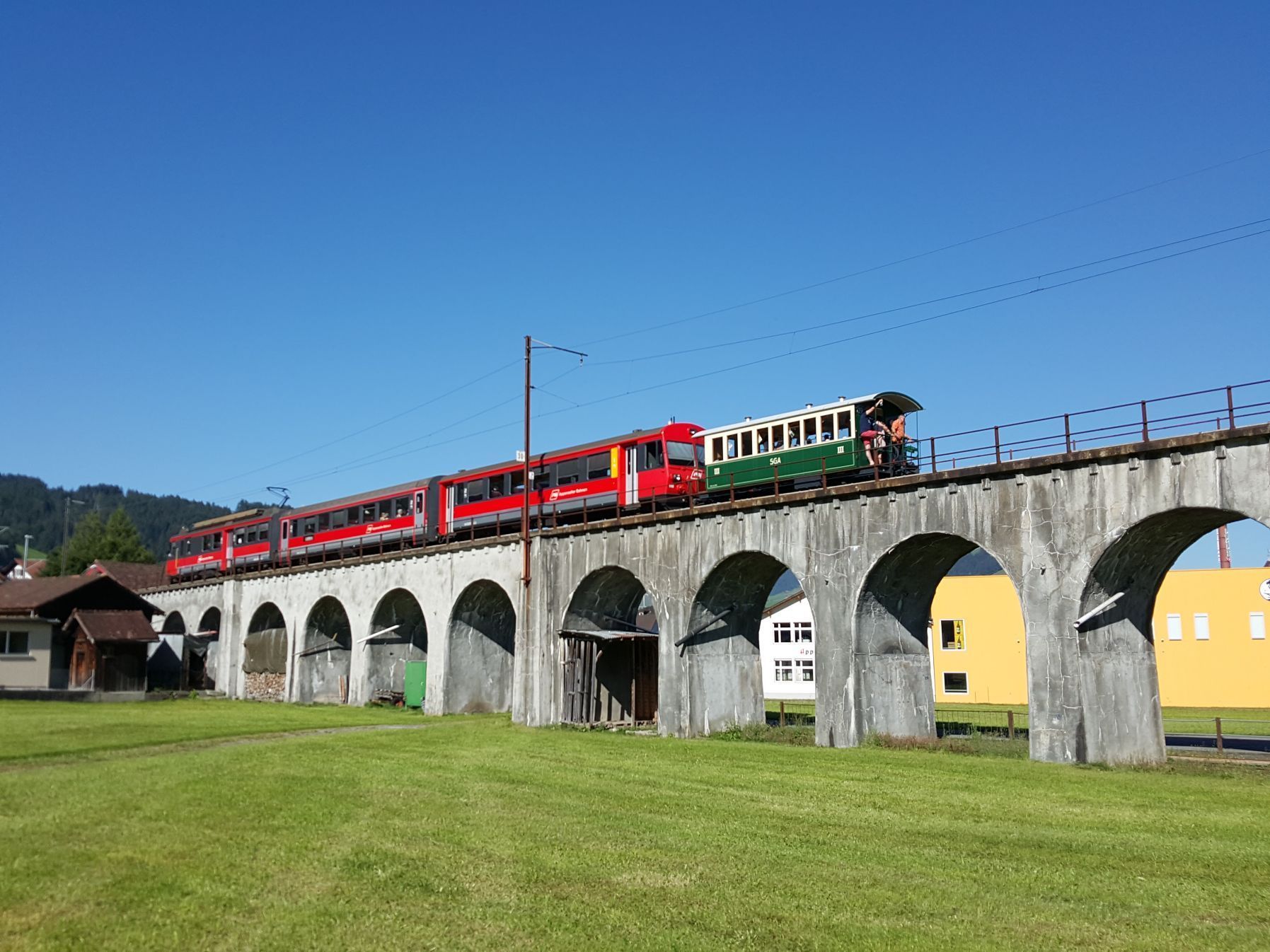 Ein Zug fährt an einem sonnigen Tag über eine Brücke