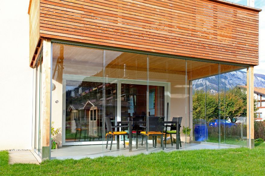 Vor einem Haus gibt es eine Terrasse mit Tisch und Stühlen.