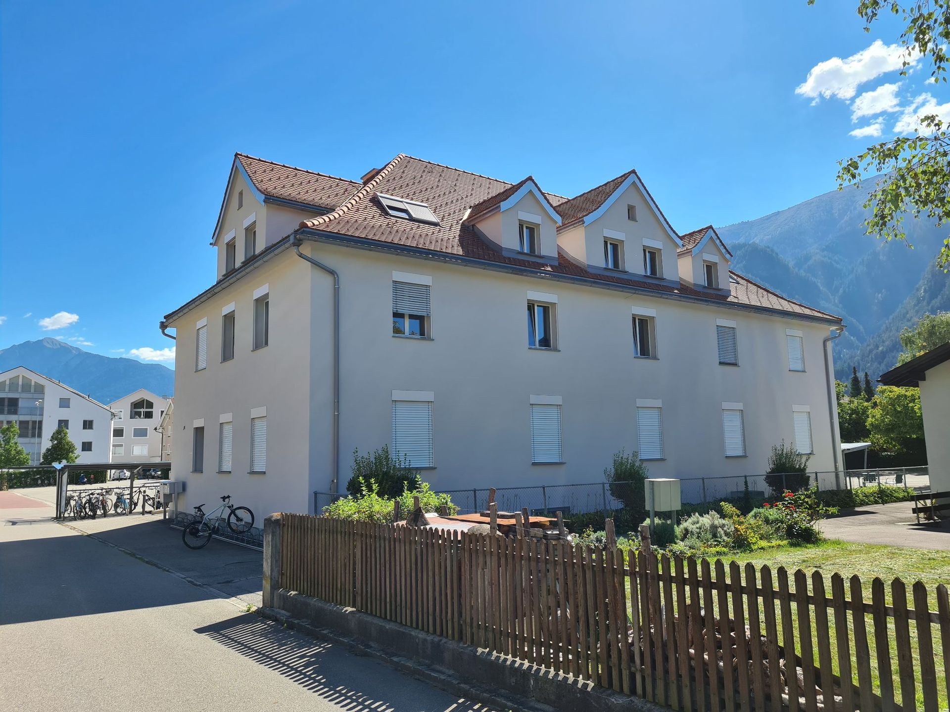 Ein großes weißes Gebäude mit einem Holzzaun davor.