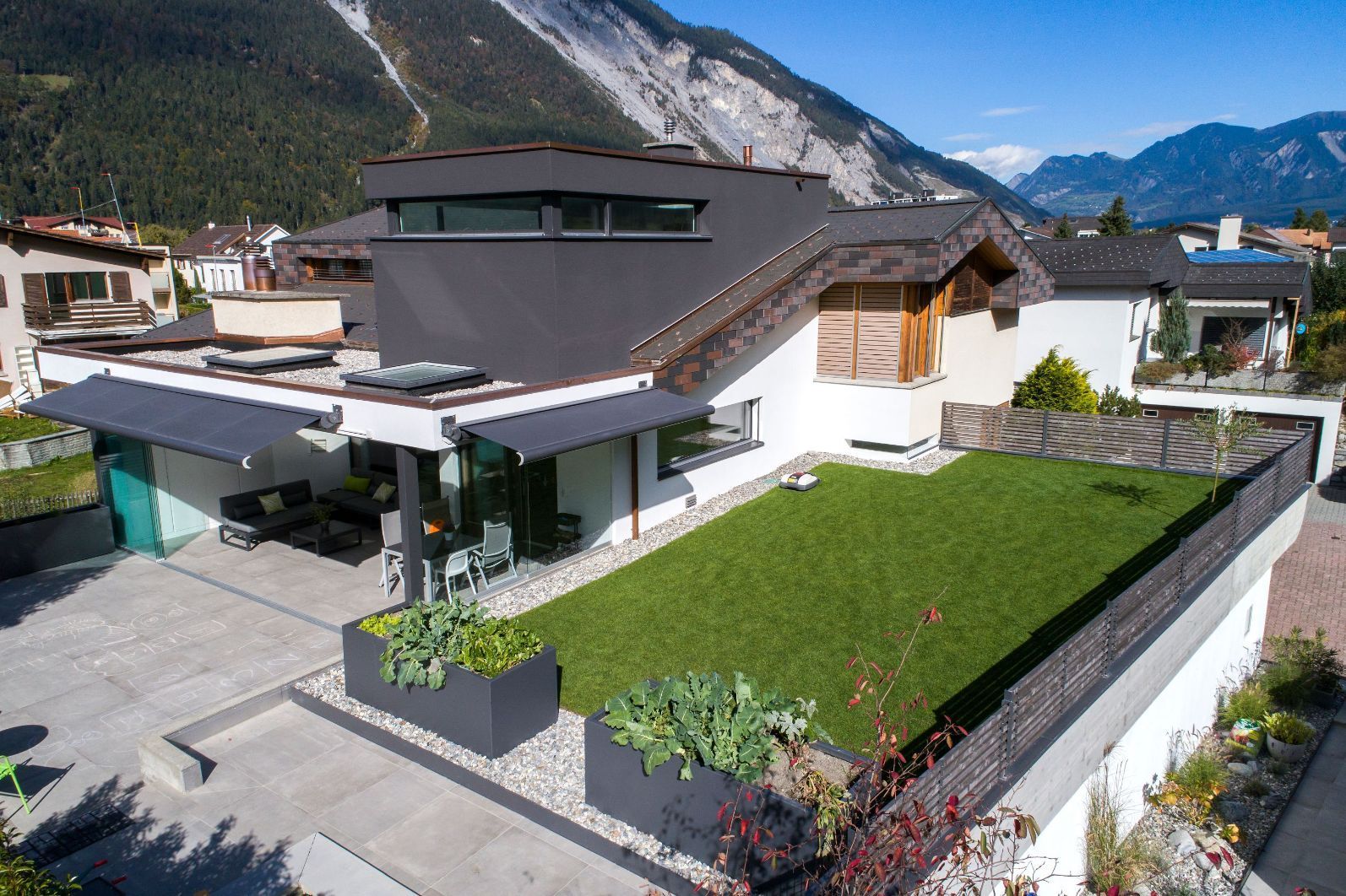 Eine Luftaufnahme eines Hauses mit einem üppigen grünen Rasen und Bergen im Hintergrund.