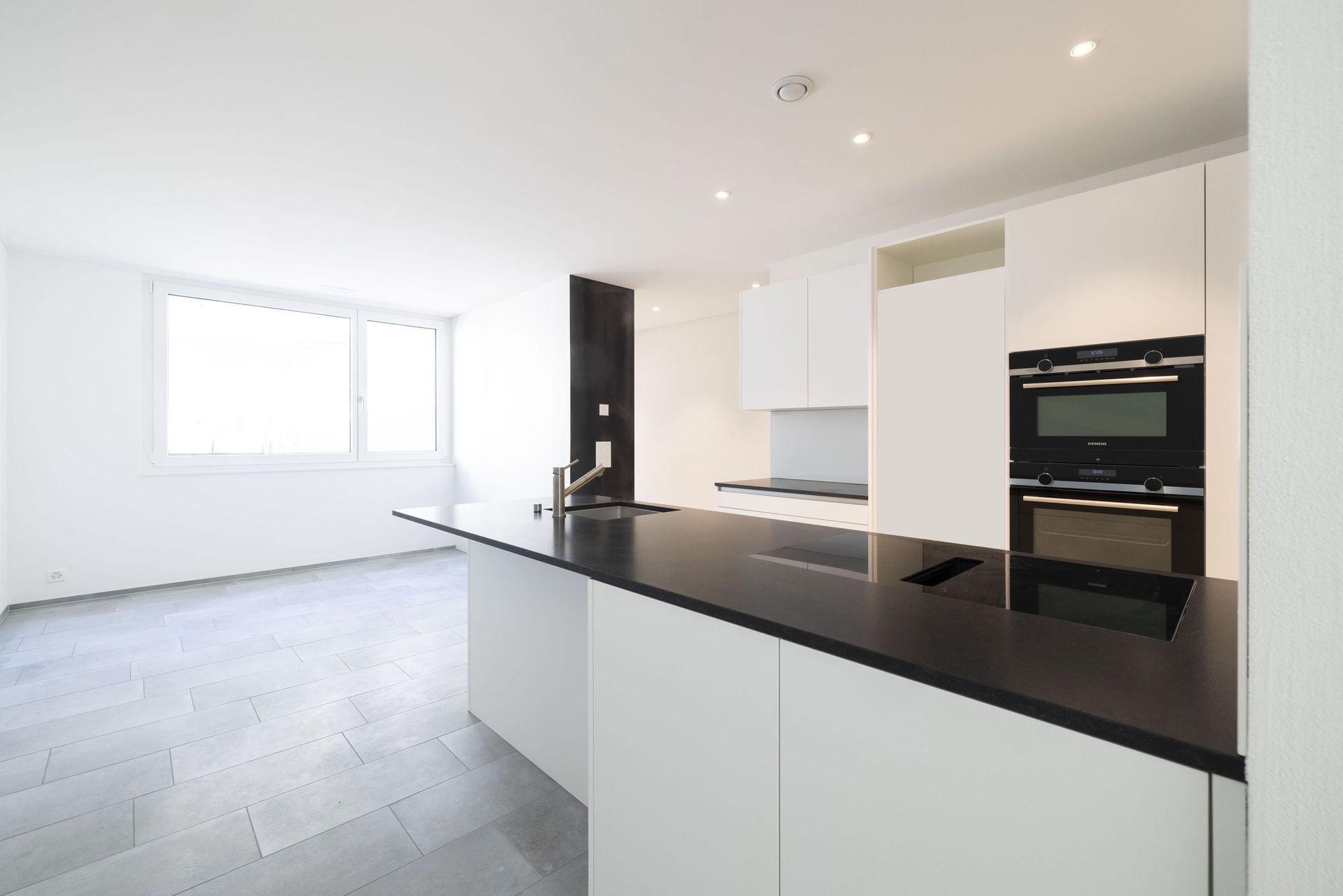 Eine leere Küche mit weißen Schränken und einer schwarzen Arbeitsplatte