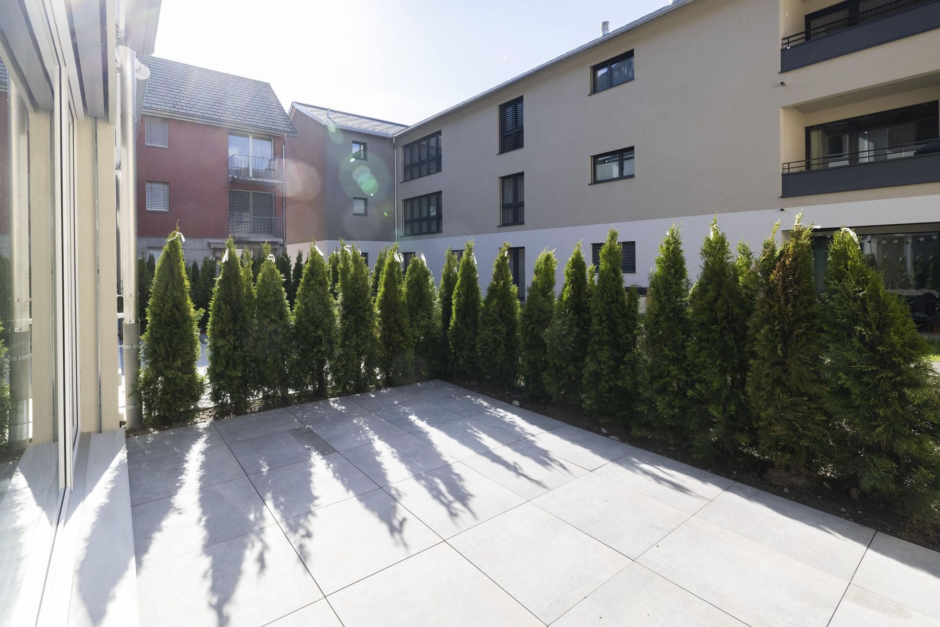 Eine Terrasse mit Bäumen und Sträuchern vor einem Gebäude