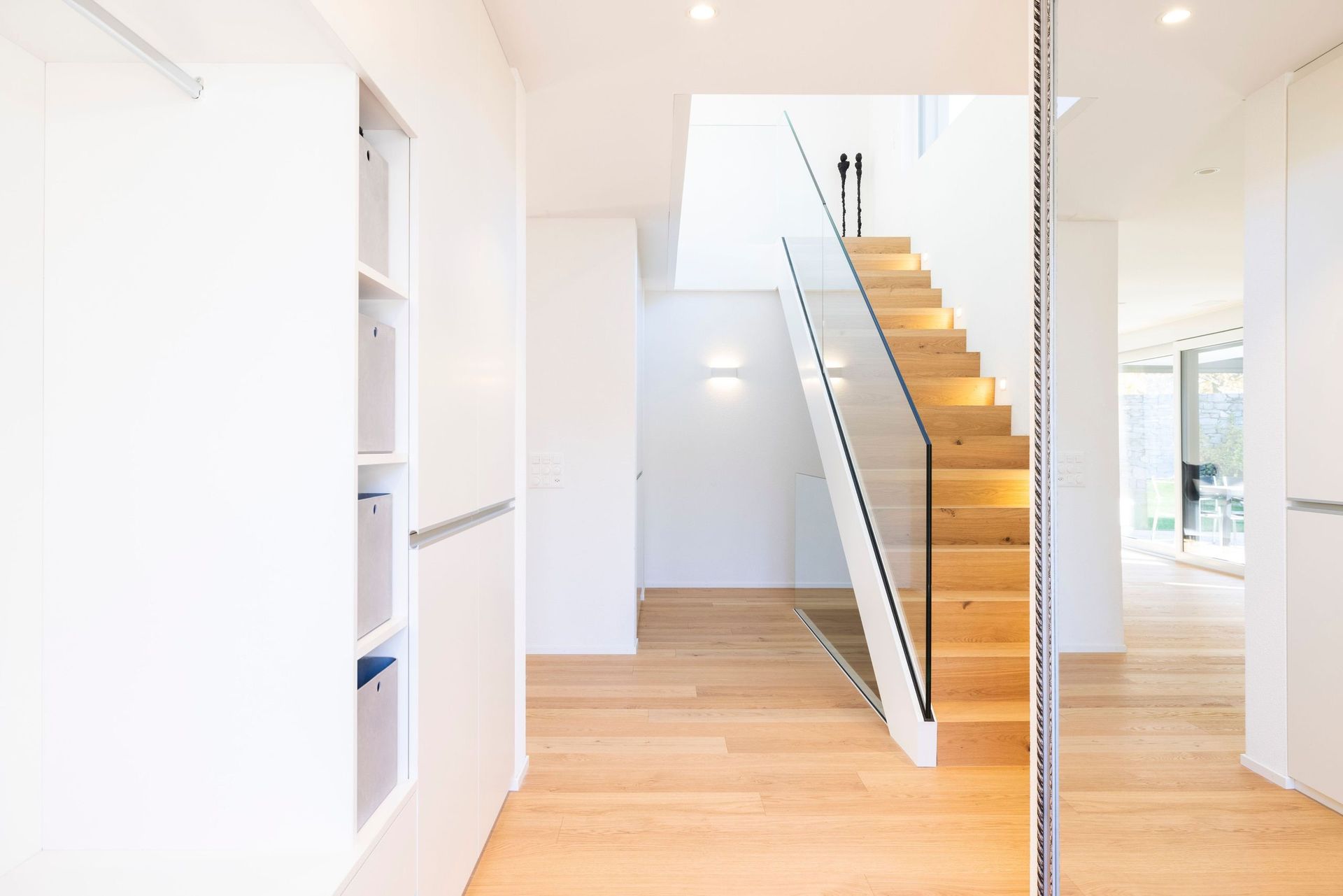 Ein Flur mit einer Holztreppe und einem Glasgeländer.