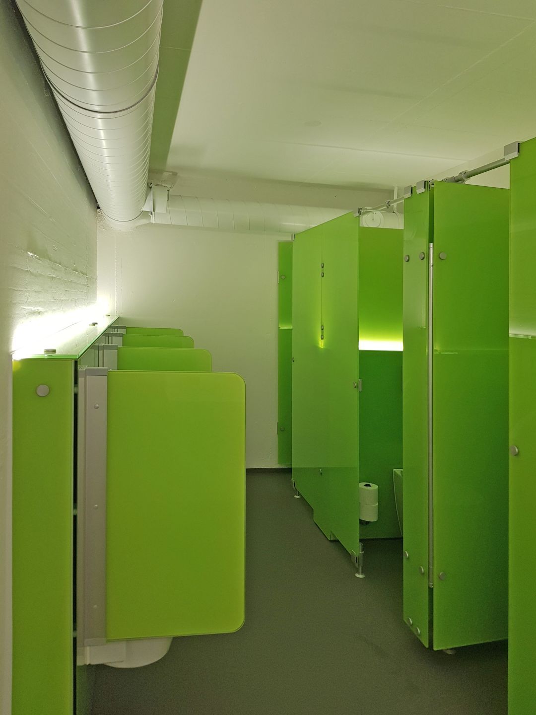 Eine Reihe grüner Kabinen in einer öffentlichen Toilette