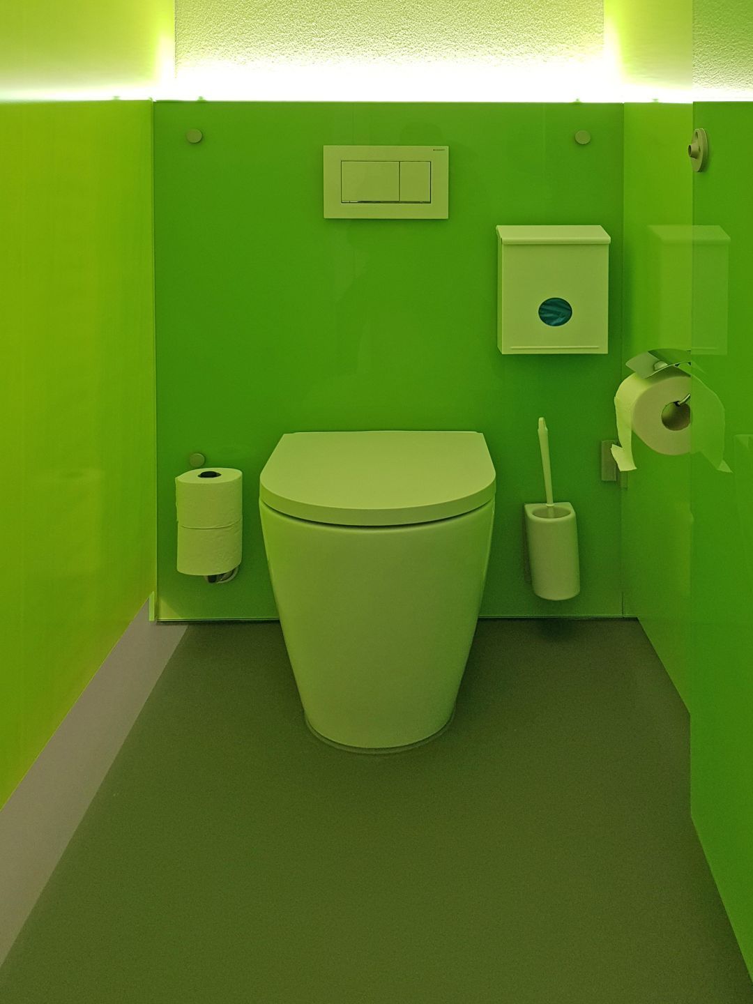 Im Badezimmer mit grünen Wänden gibt es eine Toilette.