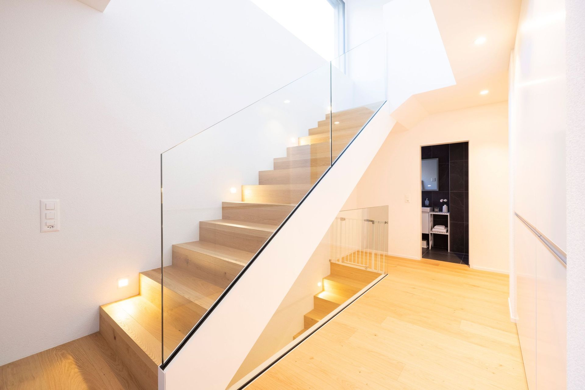 Eine moderne Treppe mit einem Glasgeländer in einem Haus.