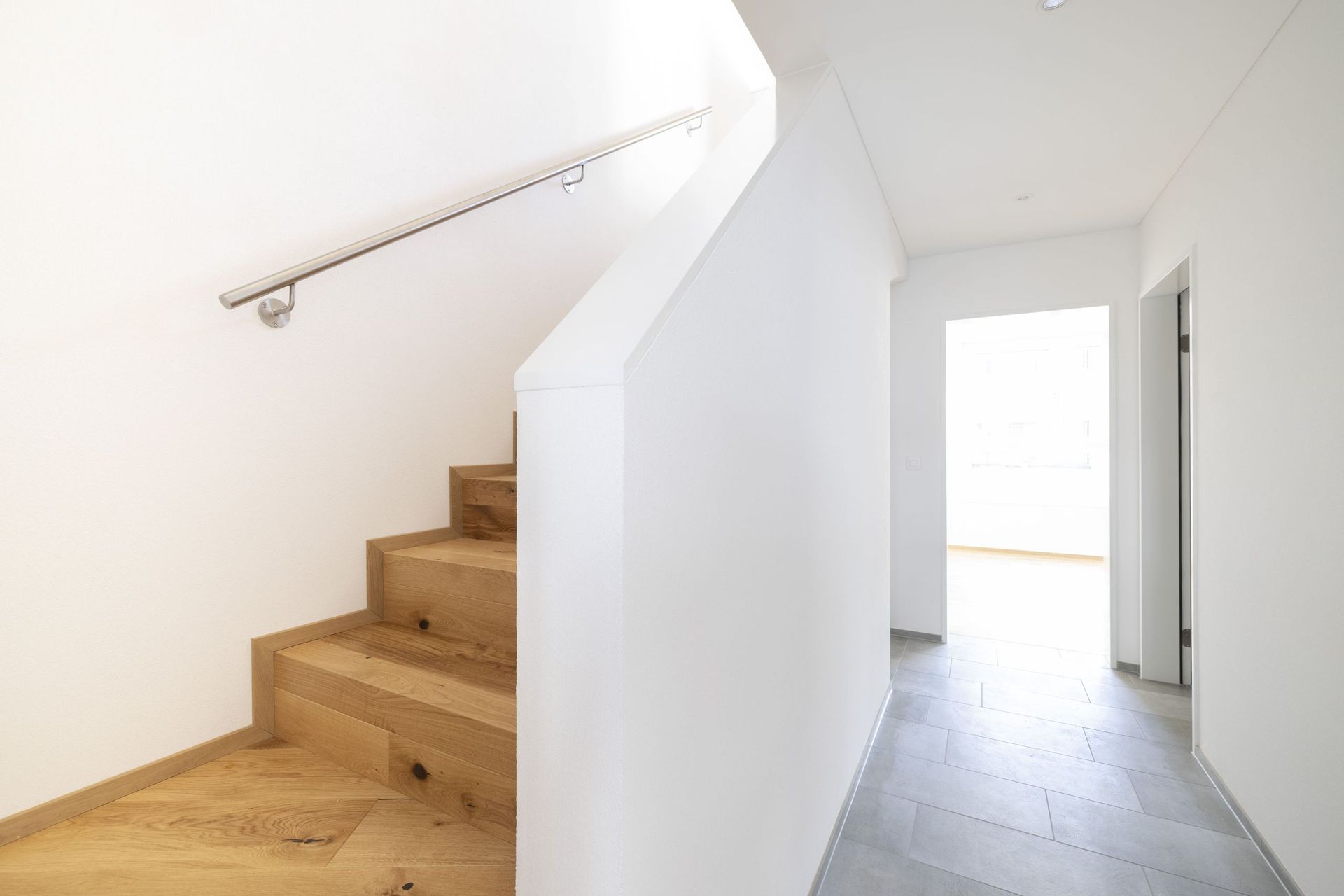 Ein Flur mit Holztreppe und einer weißen Wand.