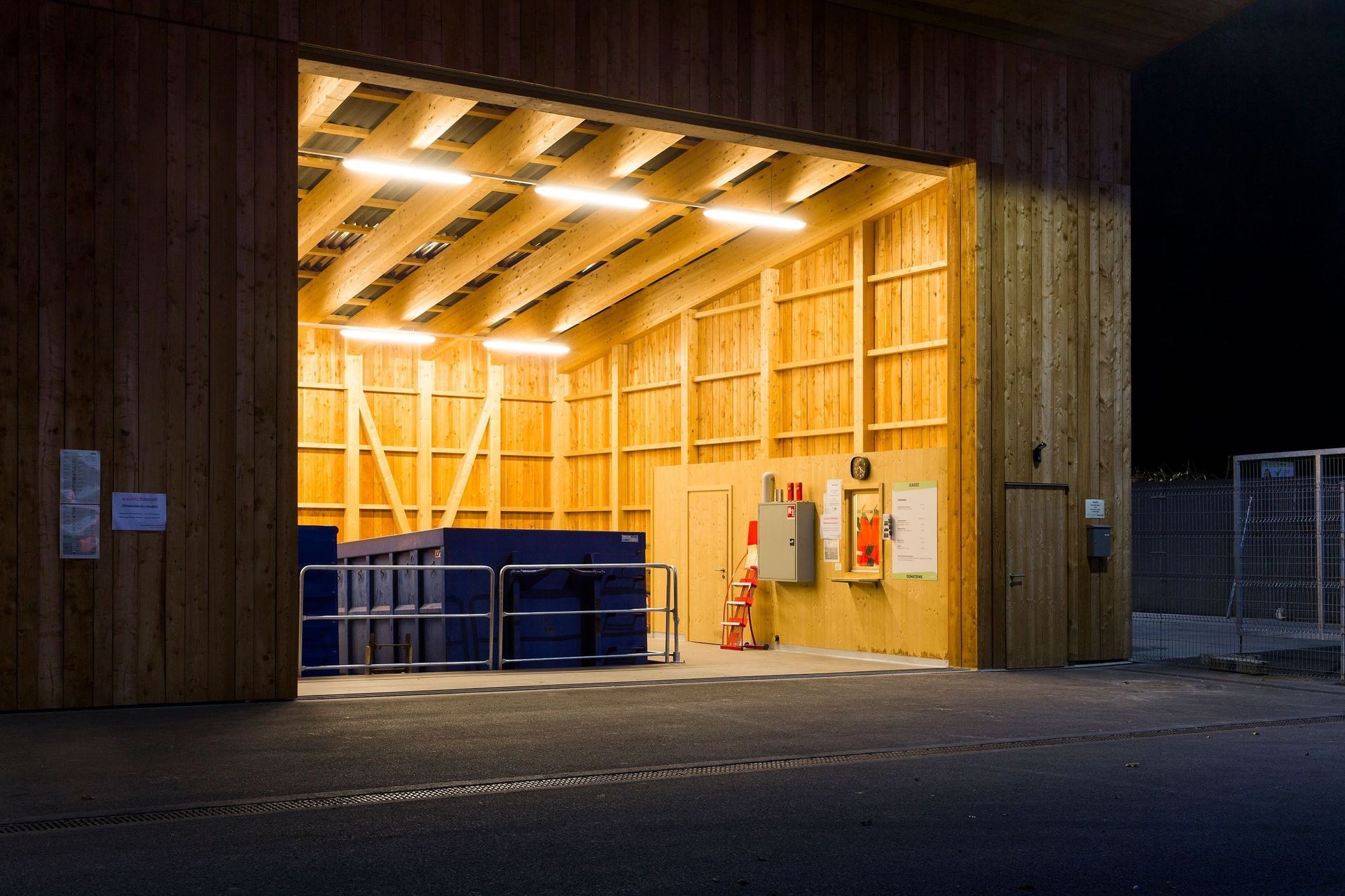 Ein großes Holzgebäude mit einer großen Tür, die nachts geöffnet ist.