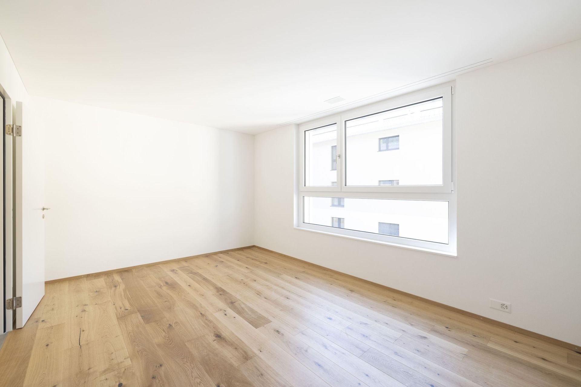 Ein leerer Raum mit Hartholzböden und zwei Fenstern.