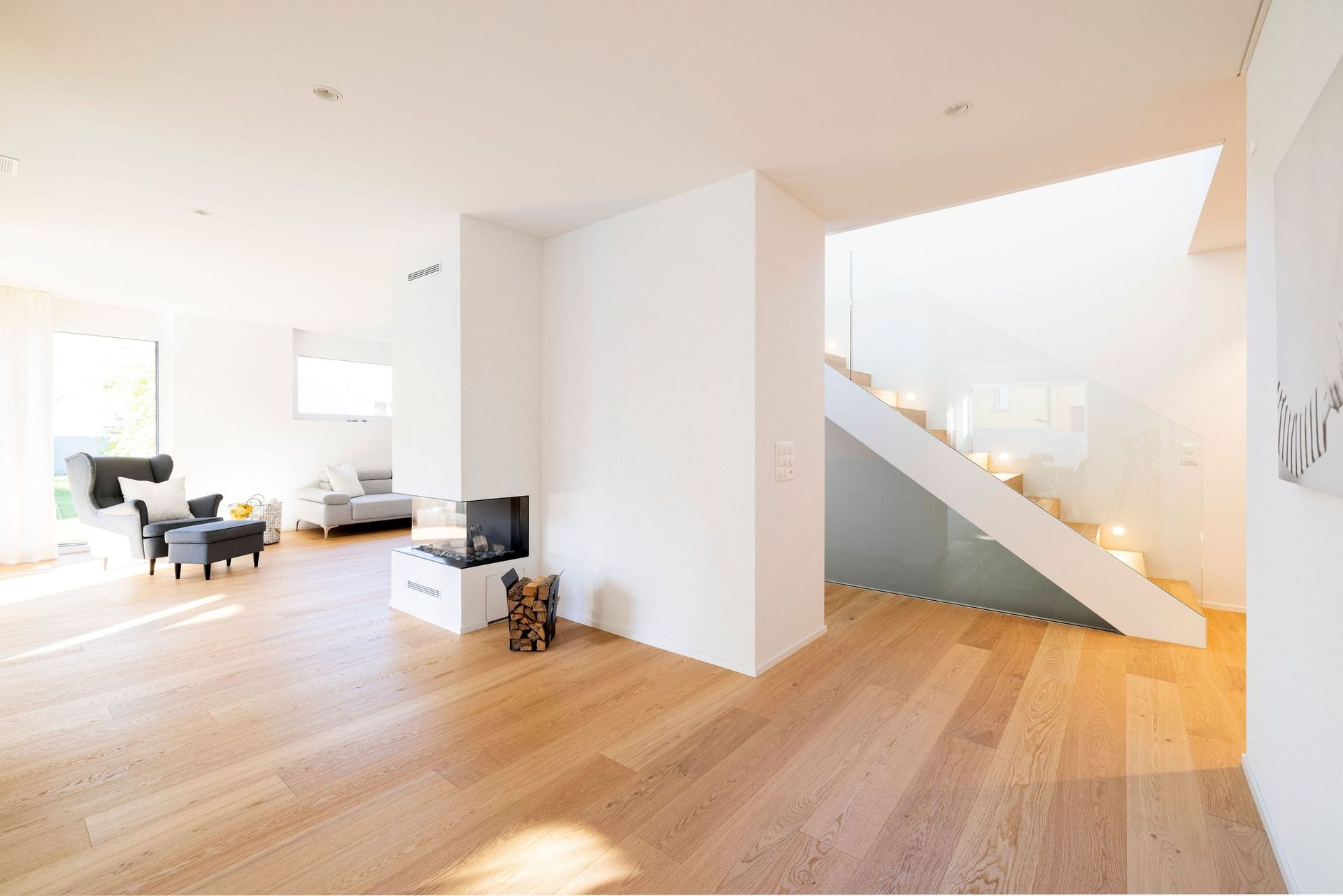 Ein Wohnzimmer mit Parkettboden und einer Treppe im Hintergrund.