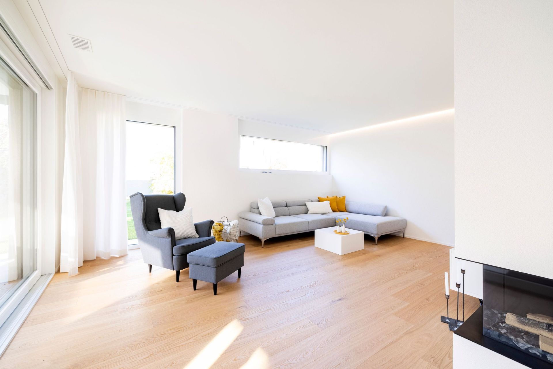 Ein Wohnzimmer mit Couch, Sessel, Couchtisch und Kamin.