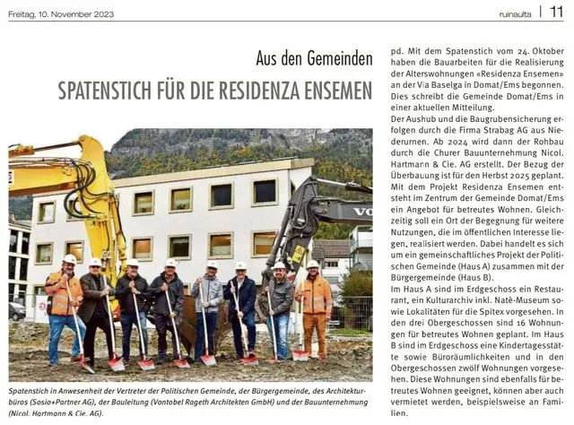 Eine Gruppe von Menschen steht mit Schaufeln vor einem Gebäude.