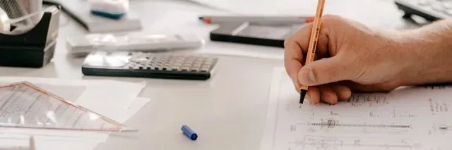 Eine Person schreibt mit einem Bleistift auf ein Blatt Papier.