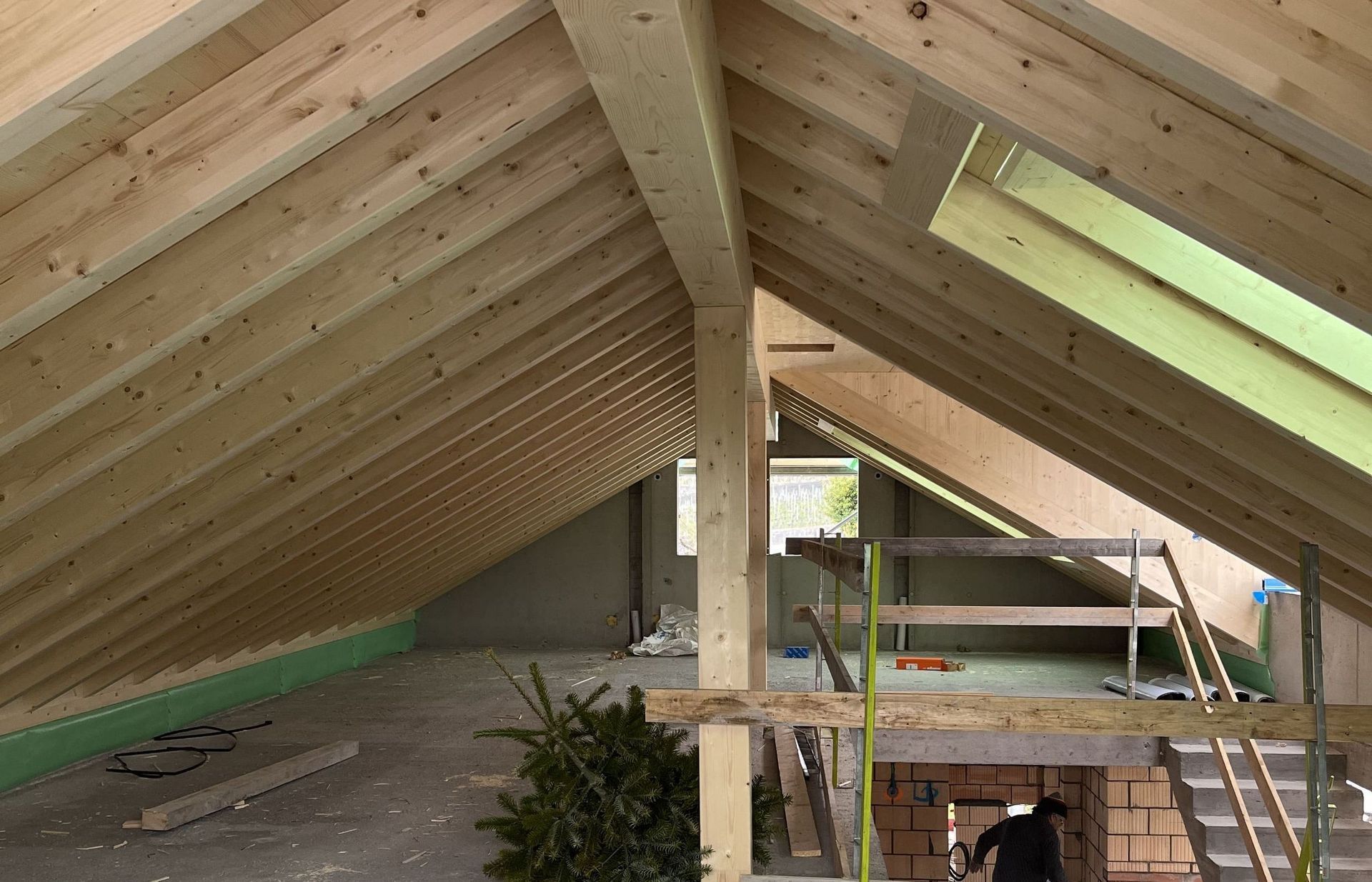 Ein Mann steht auf dem Dachboden eines im Bau befindlichen Hauses.