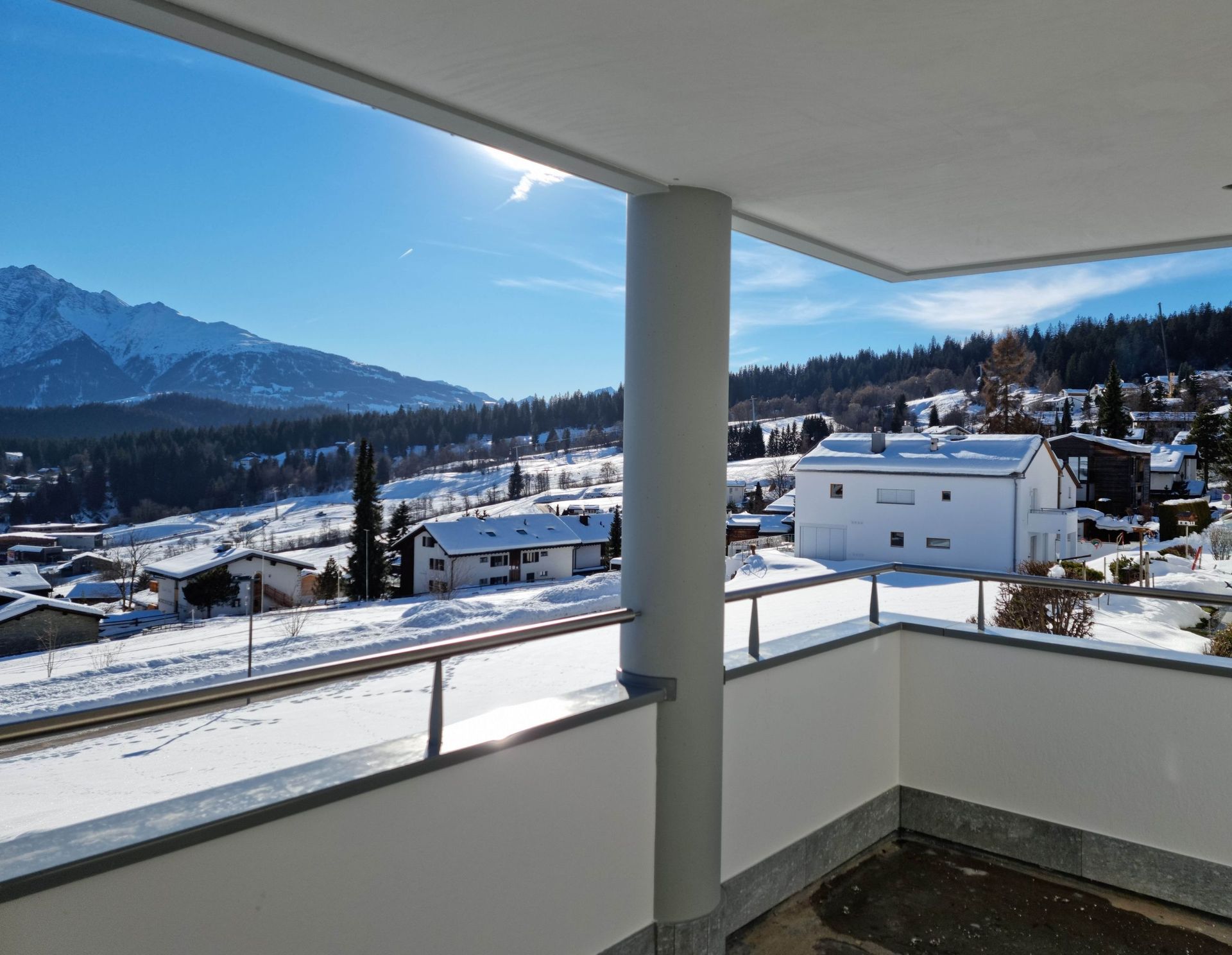 Ein Balkon mit Blick auf ein verschneites Dorf und Berge