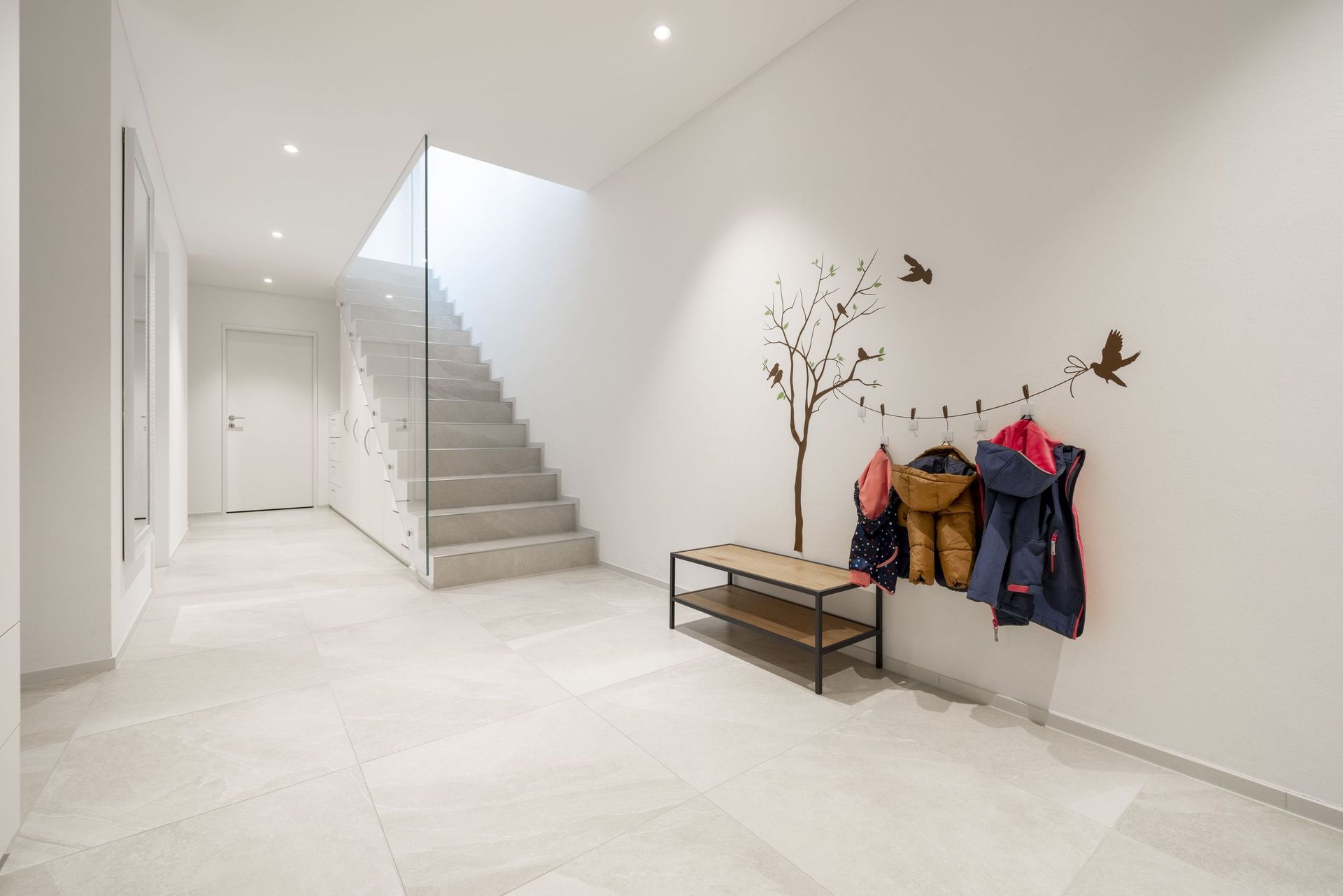 Ein Flur mit Treppe und einer Bank mit an der Wand hängenden Jacken.