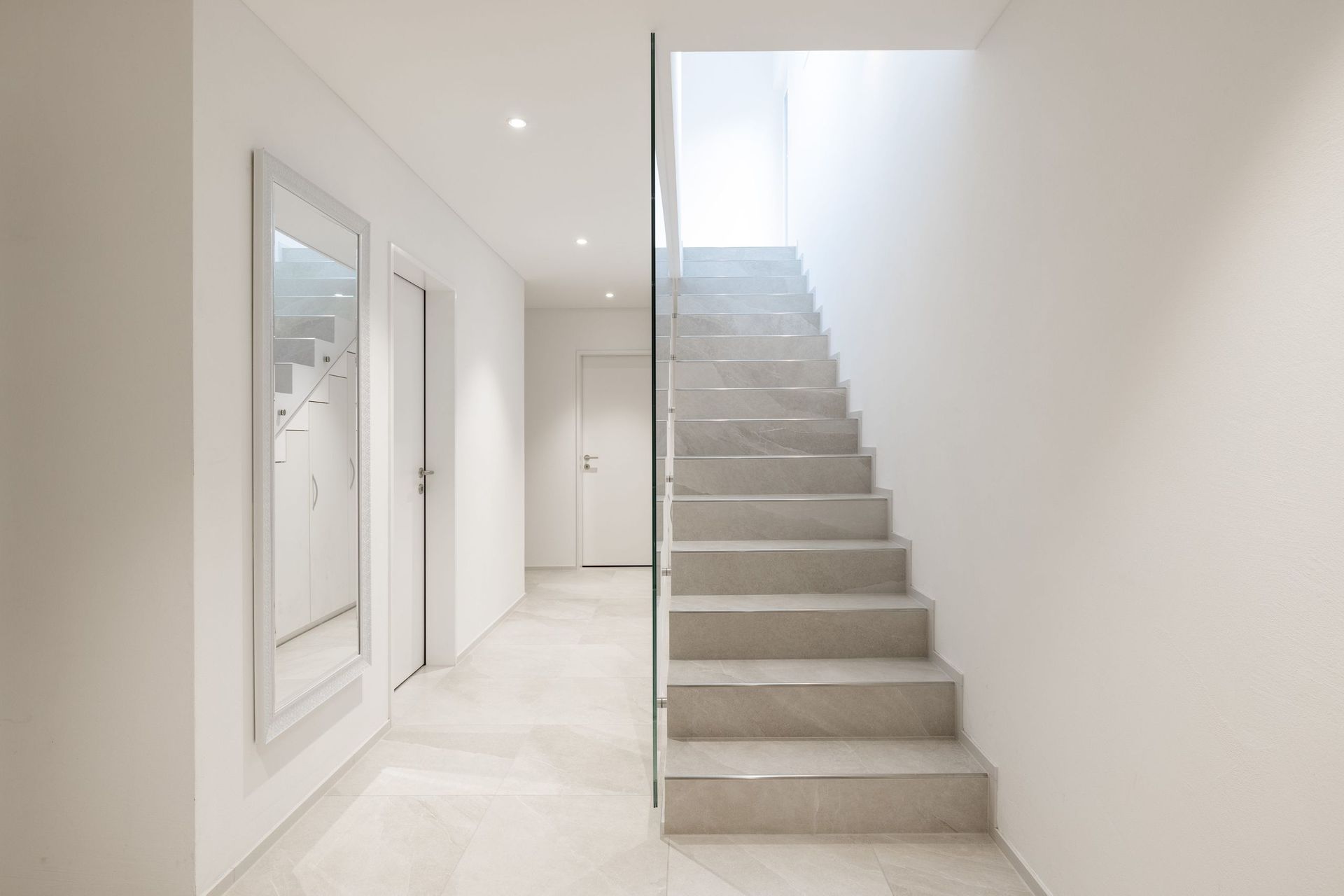 Ein Flur mit einer Treppe und einem Spiegel an der Wand.