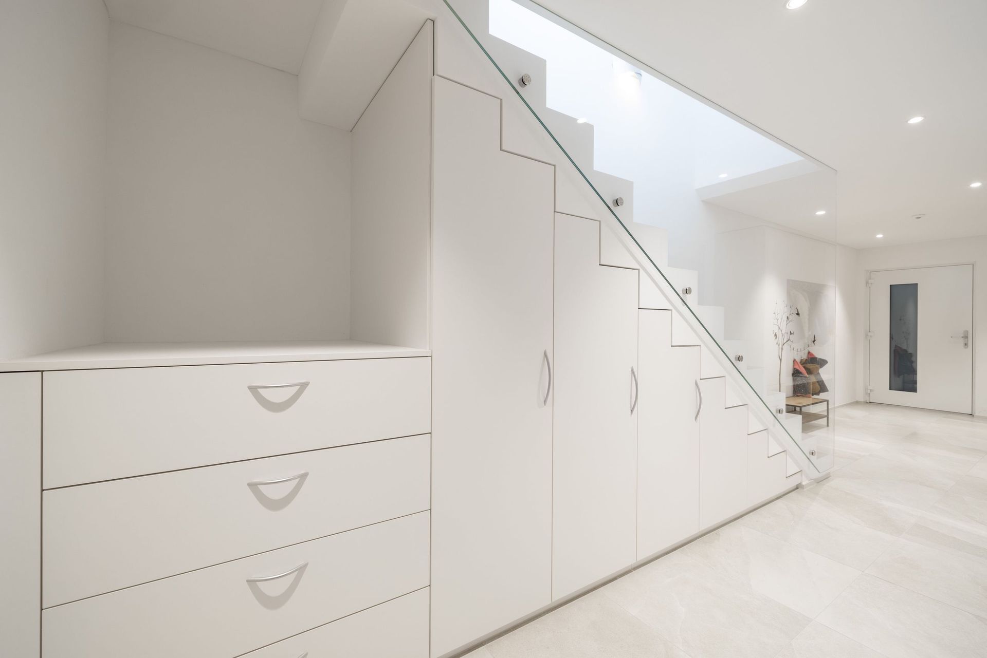 Ein Flur mit Treppe und Schubladen darunter.