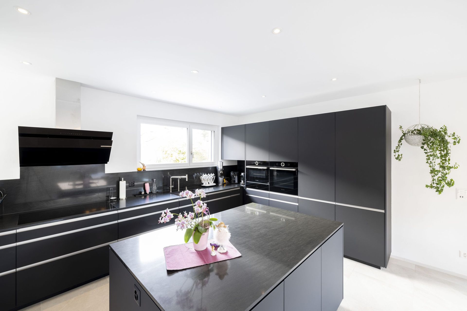 Eine Küche mit schwarzen Schränken und einer großen Insel in der Mitte.