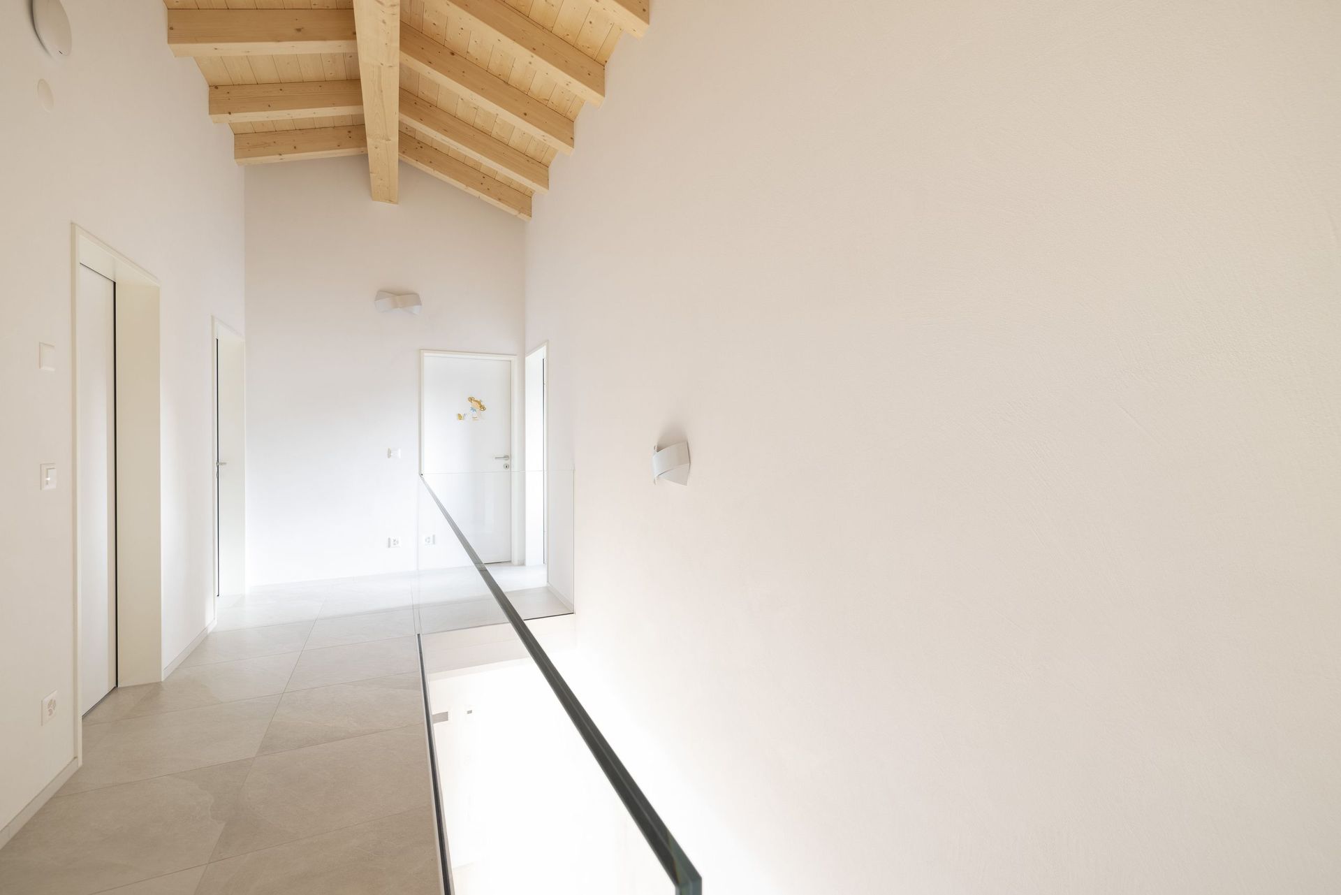 Ein langer Flur mit Holzdecke und weißen Wänden