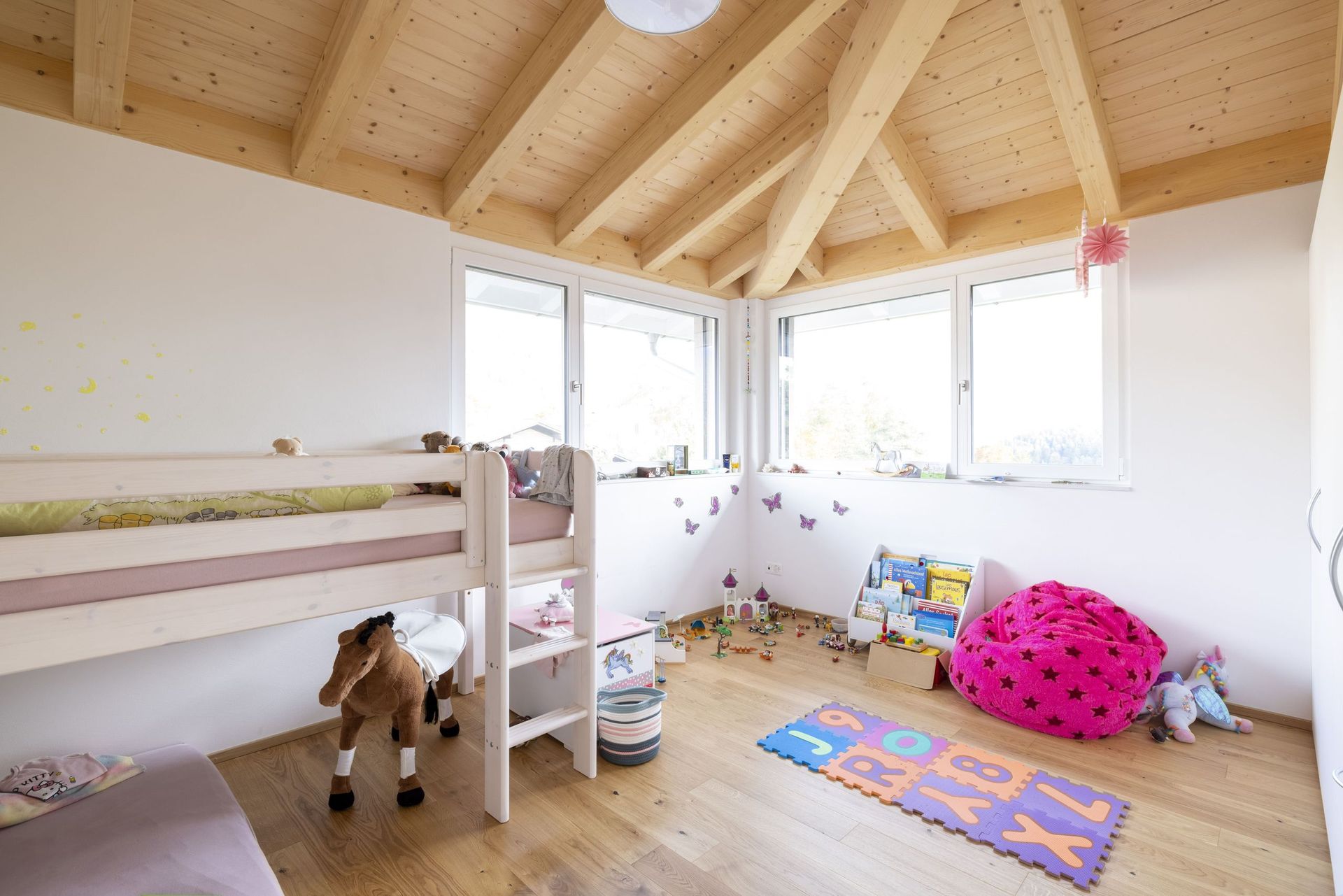 Ein Kinderzimmer mit Etagenbett und vielen Fenstern.