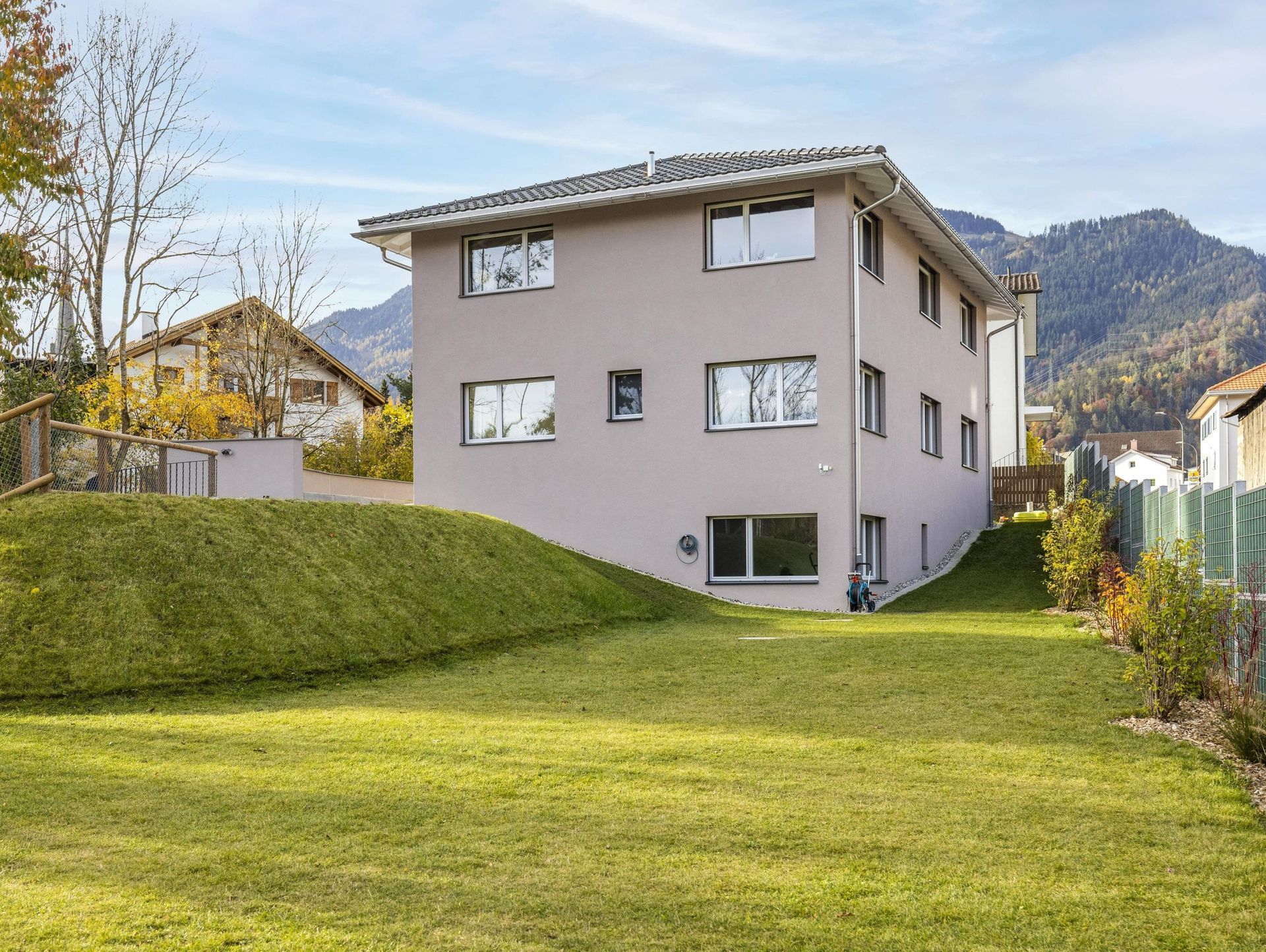 Auf einem üppig grünen Hügel steht ein großes Haus mit vielen Fenstern.