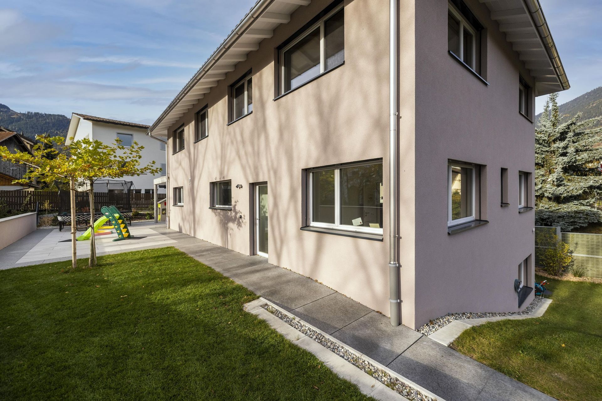 Ein großes Haus mit vielen Fenstern und einem Spielplatz im Hinterhof.