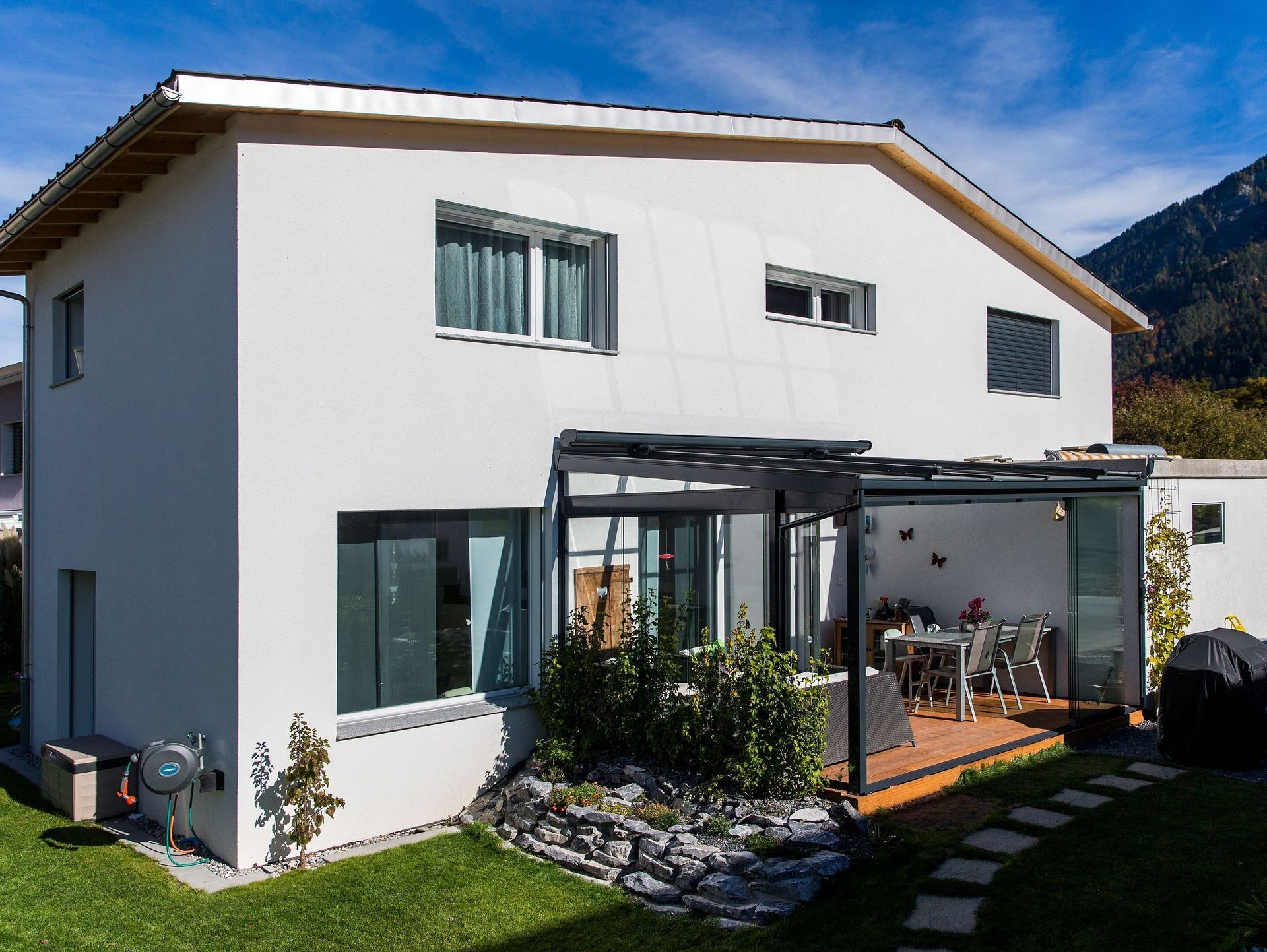 Ein weißes Haus mit einer Pergola im Hinterhof