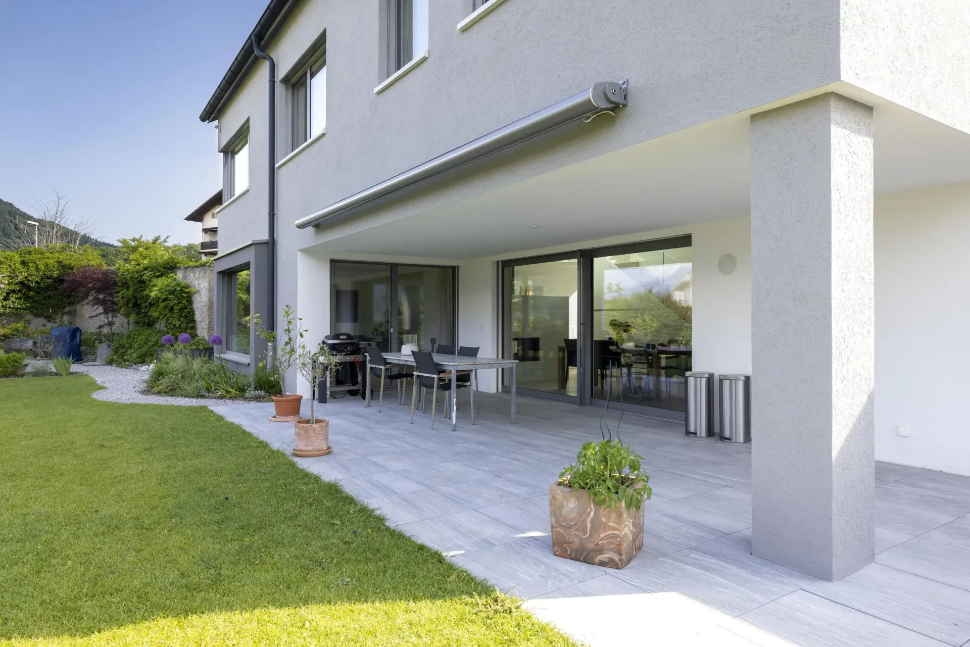 Ein großes Haus mit Terrasse und Rasen davor.