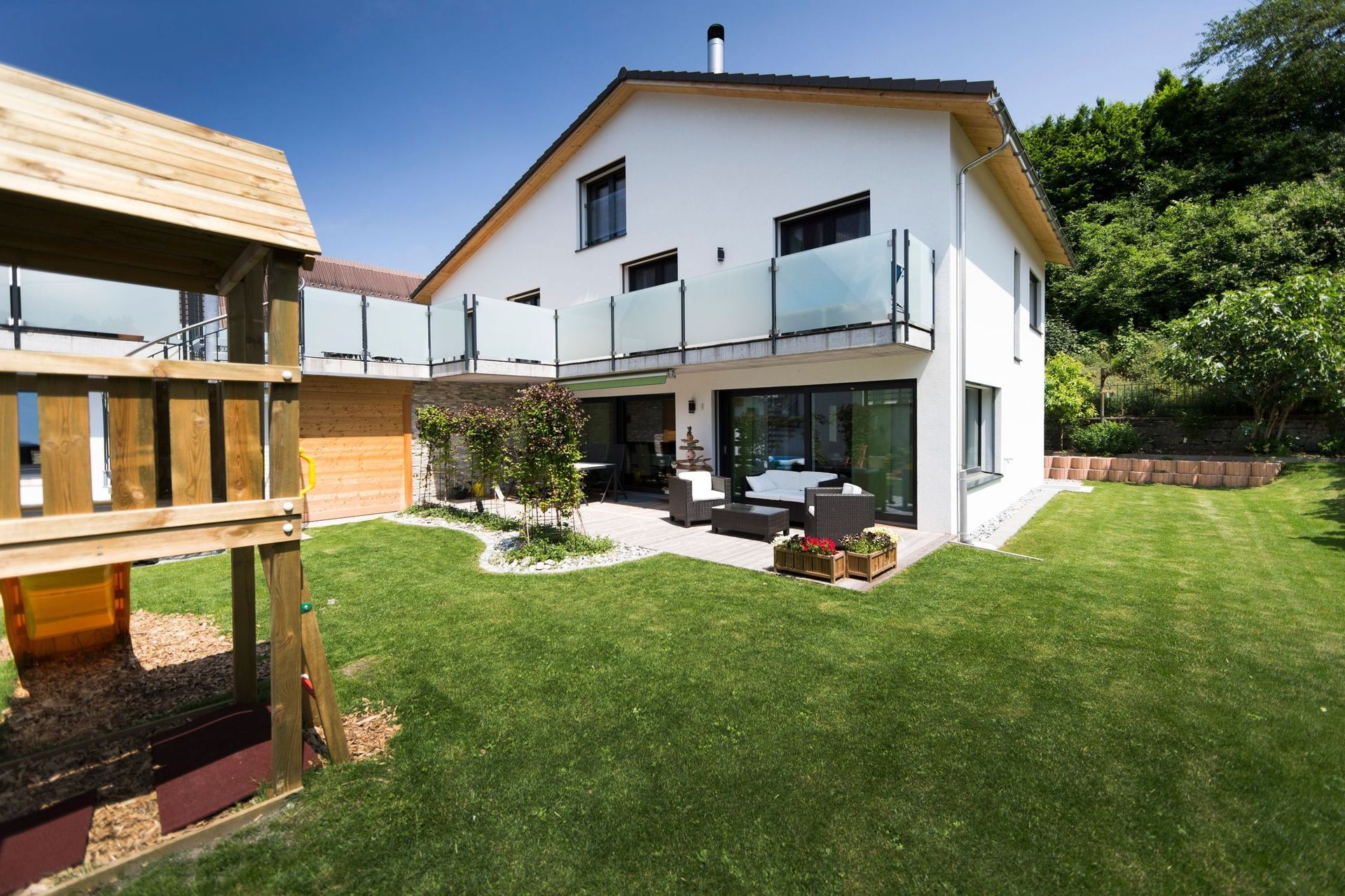 Ein großes weißes Haus mit einem hölzernen Spielplatz davor